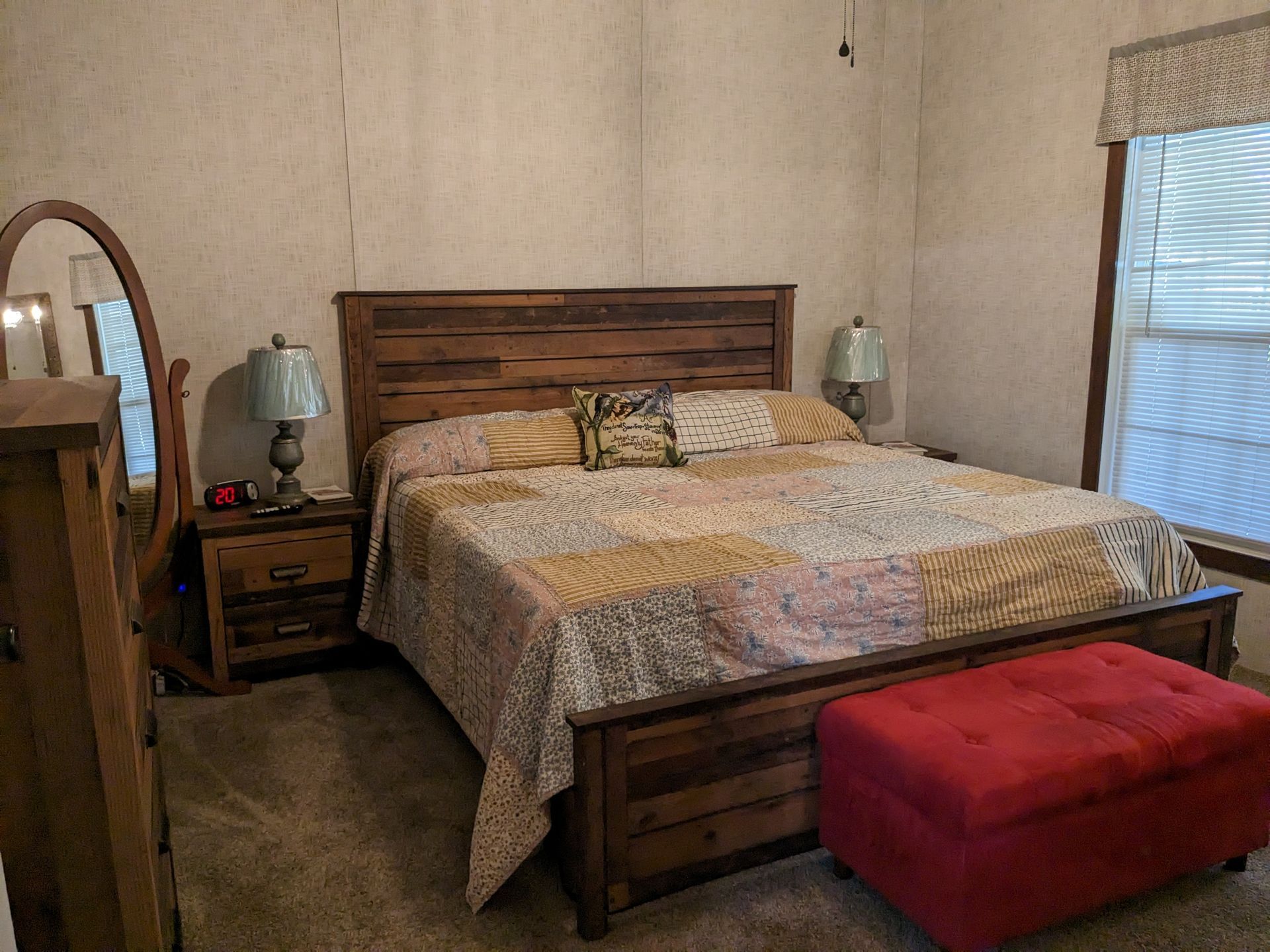 Bedroom with a wooden bed, nightstands, a mirror, and a red ottoman in a Florida animal farm