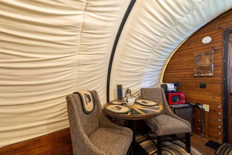Interior of a covered wagon with two chairs, small table, and a mini-fridge. Beige canvas walls in a Florida animal farm