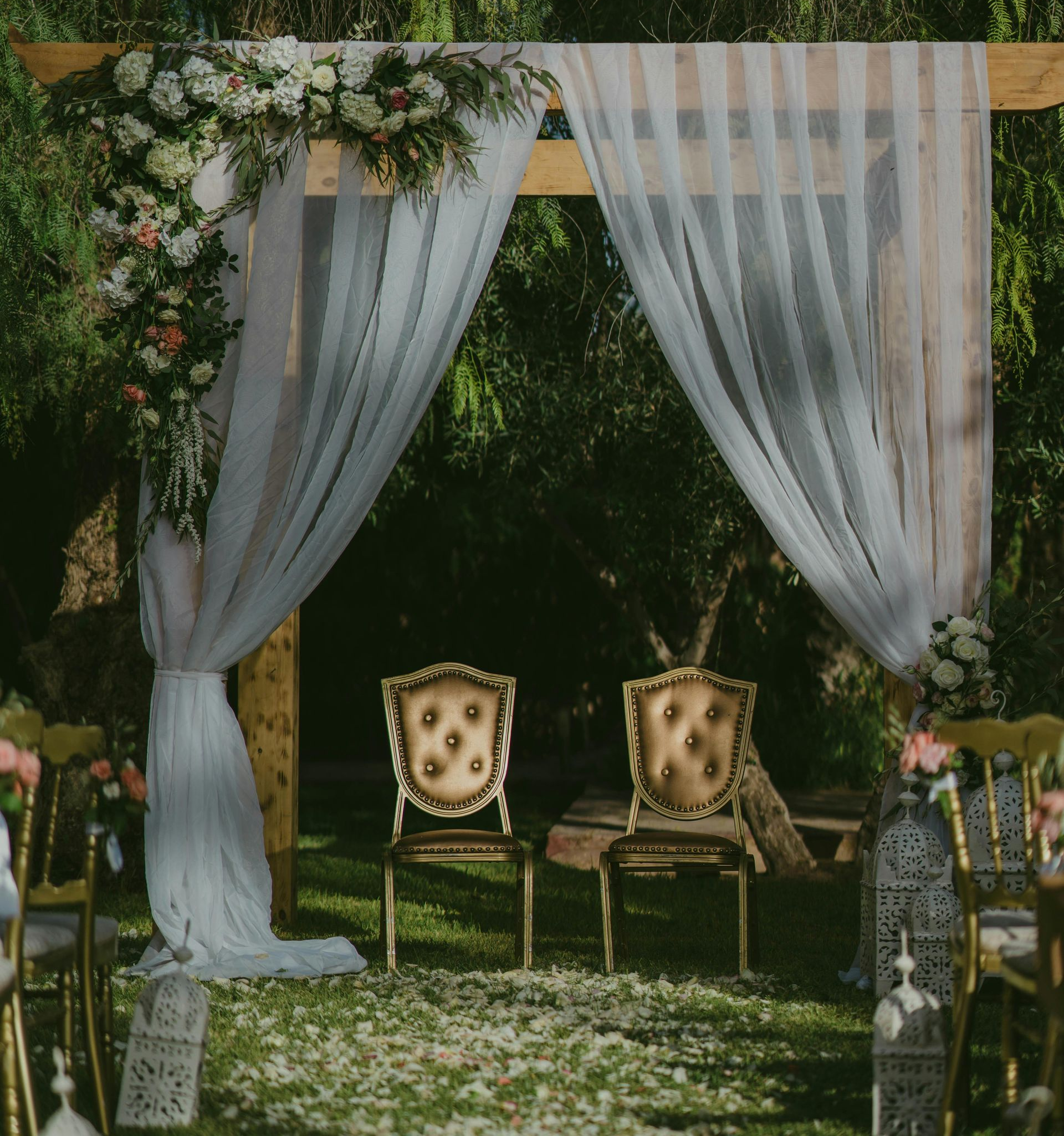 Wedding arch draped with white fabric and flowers, two ornate chairs sit inside in a Florida animal farm
