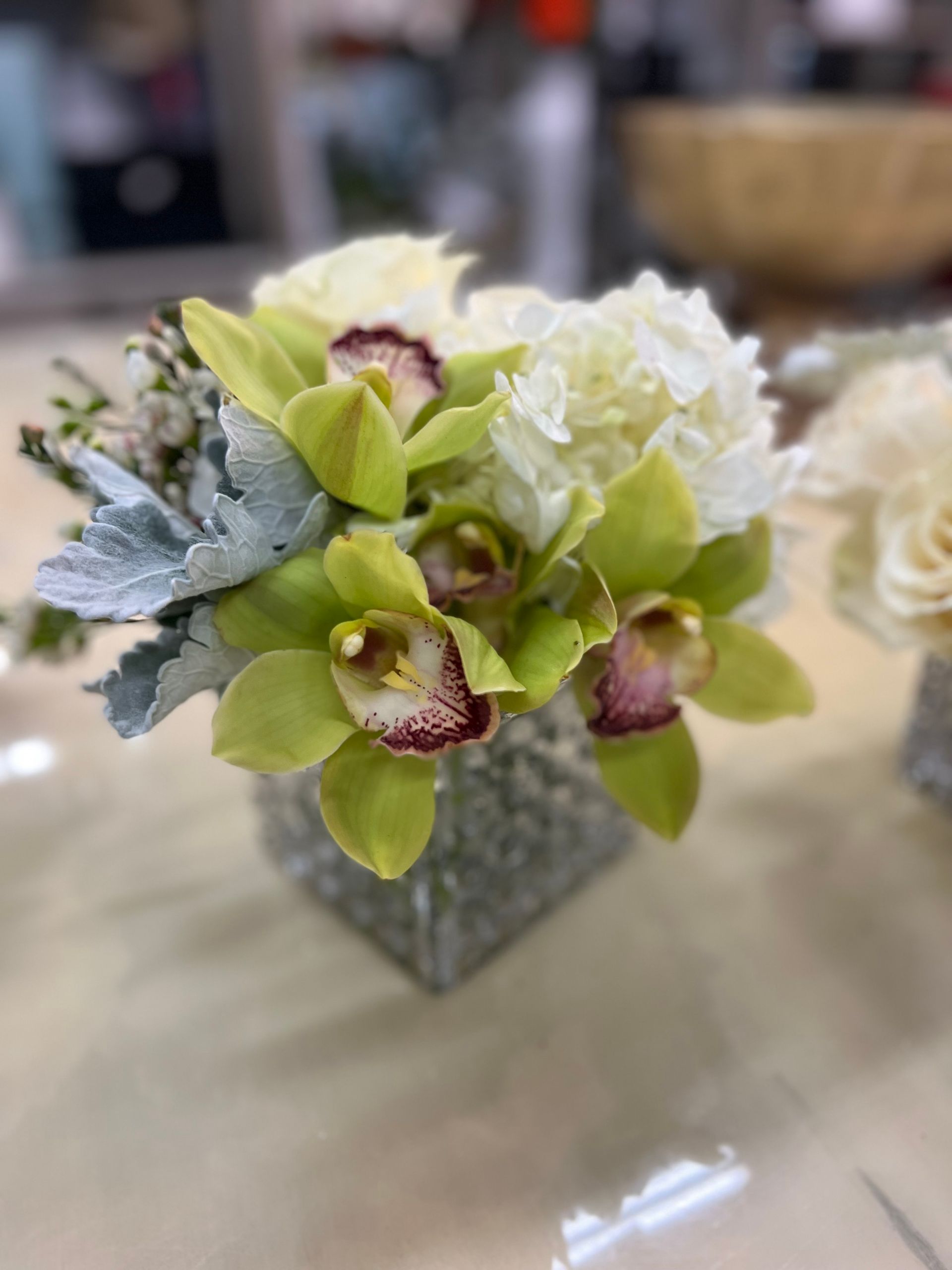 A vase filled with green and white flowers is sitting on a table.