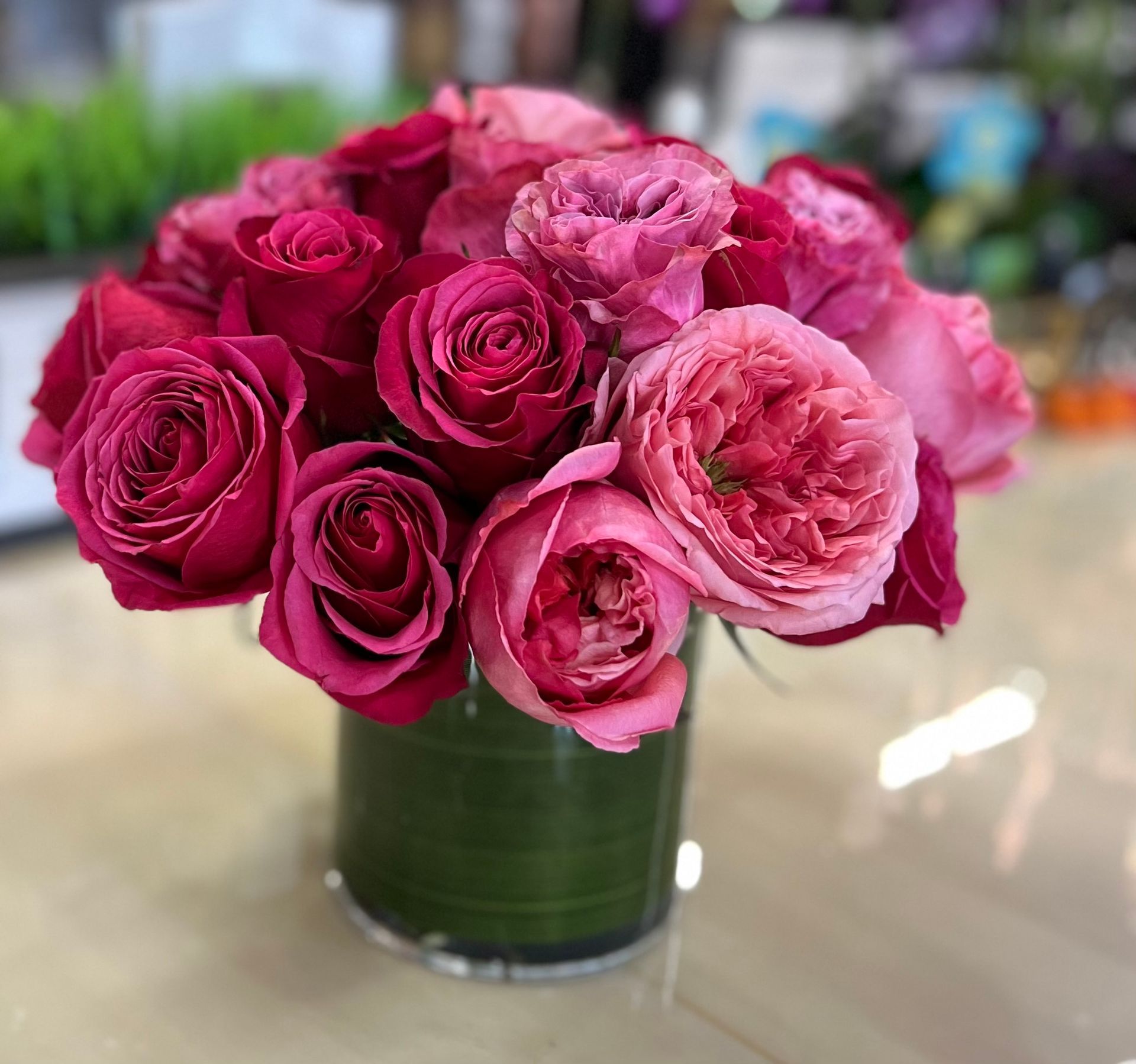 A vase filled with pink roses is sitting on a table.