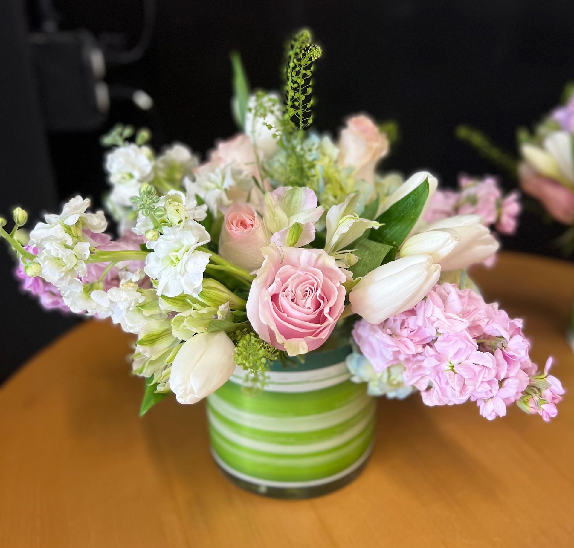 A green vase filled with pink and white flowers