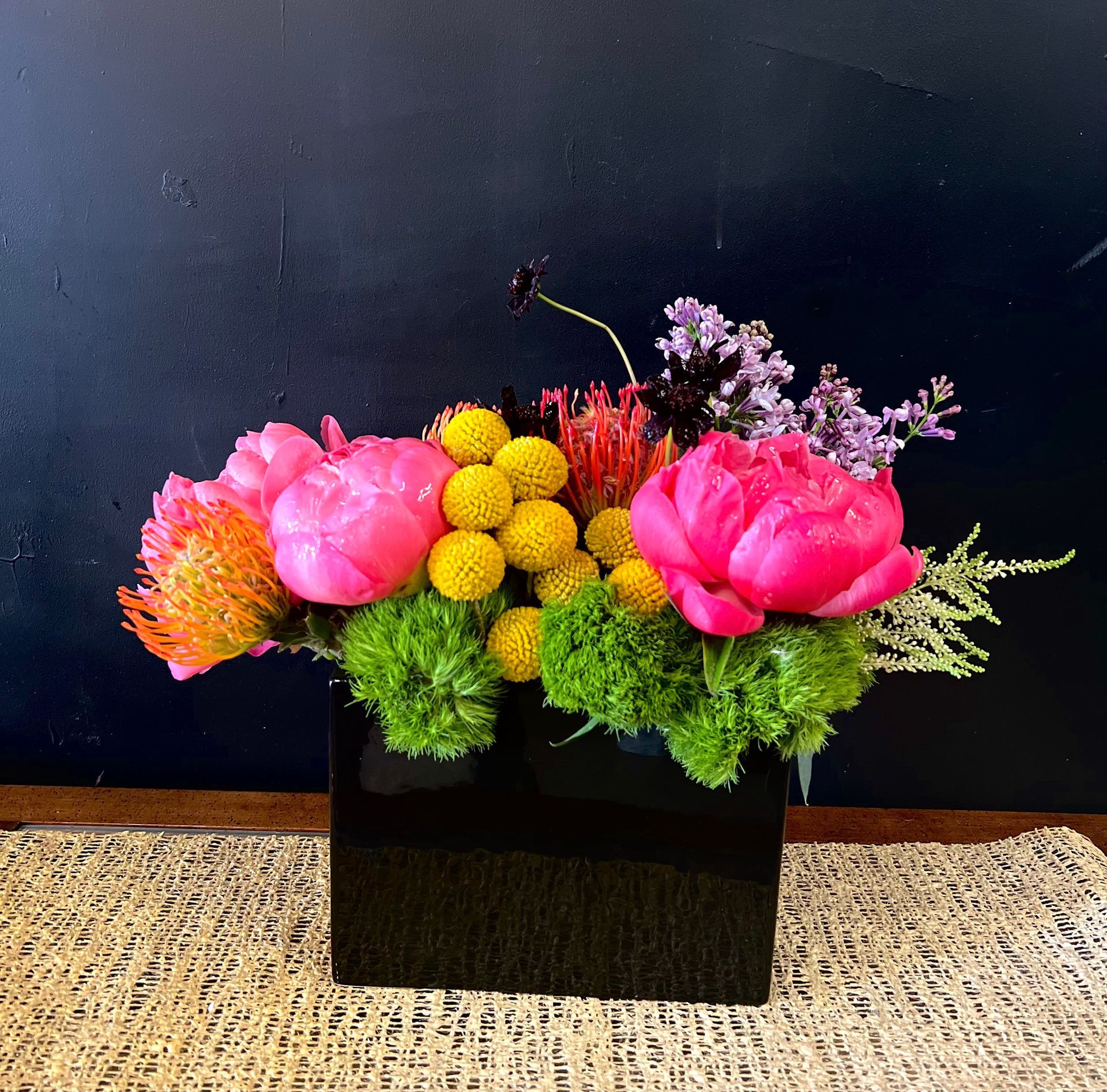 A black vase filled with pink and yellow flowers