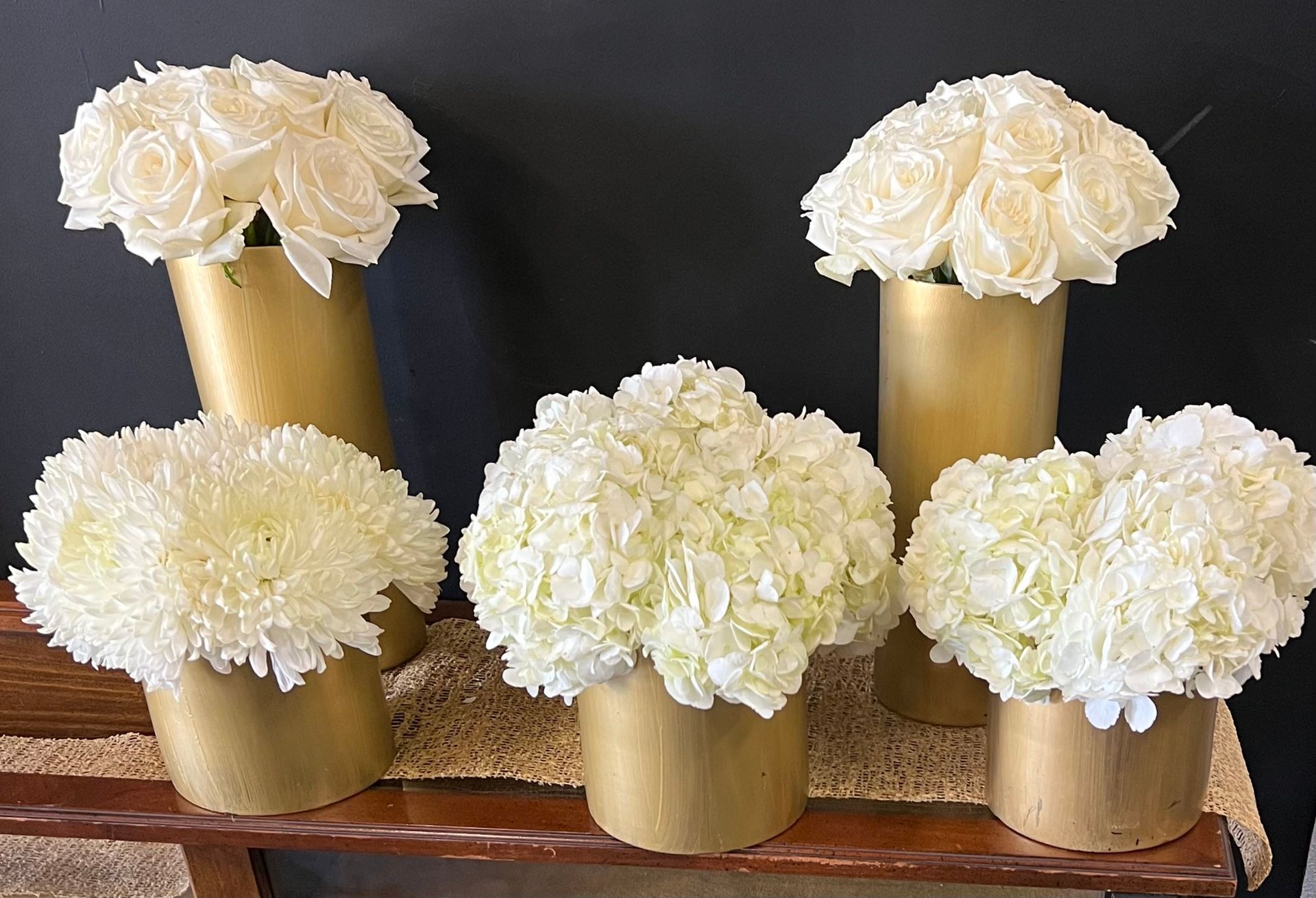 Three vases filled with white flowers are sitting on a table.