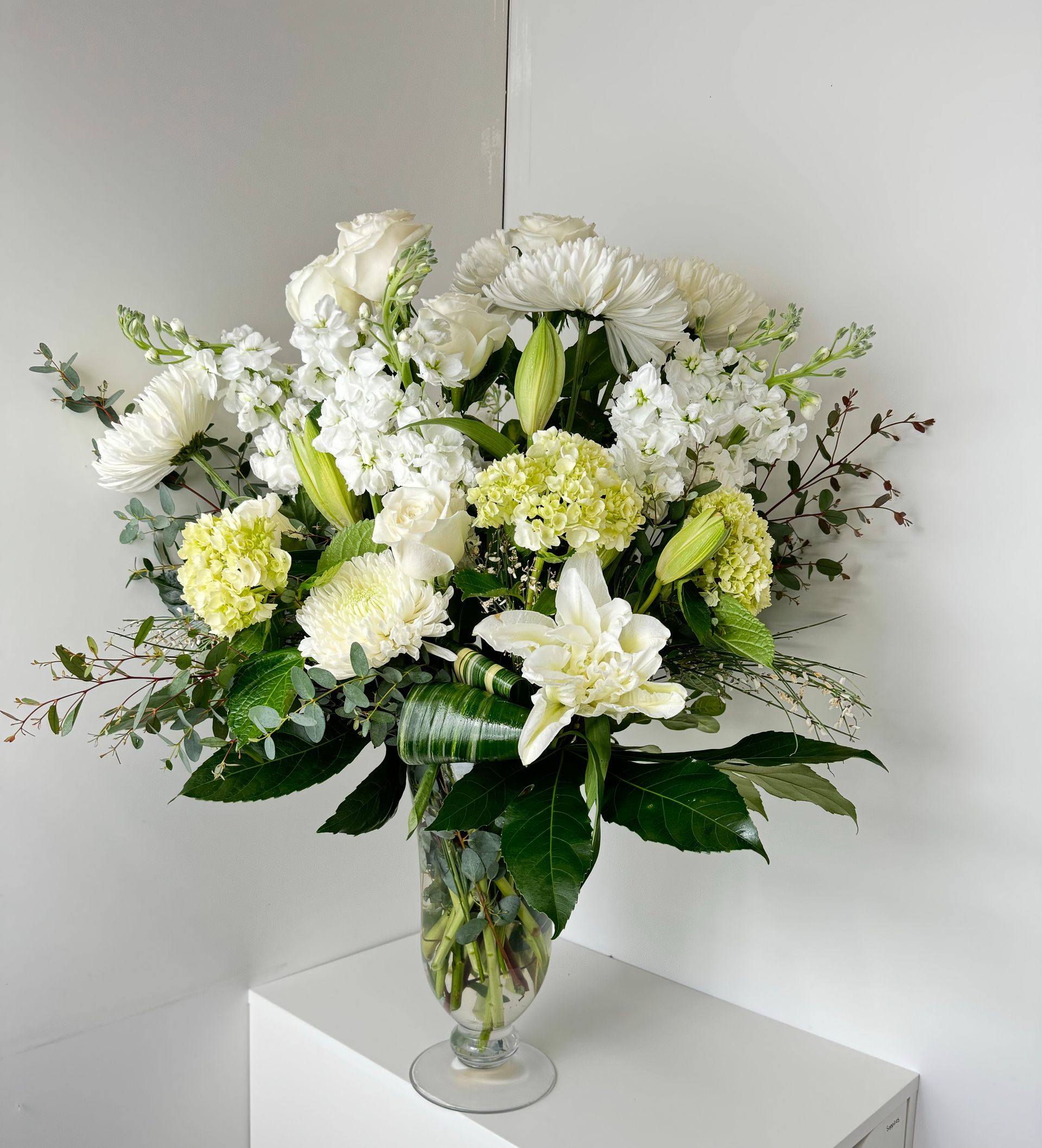 A vase filled with white and yellow flowers is sitting on a table.