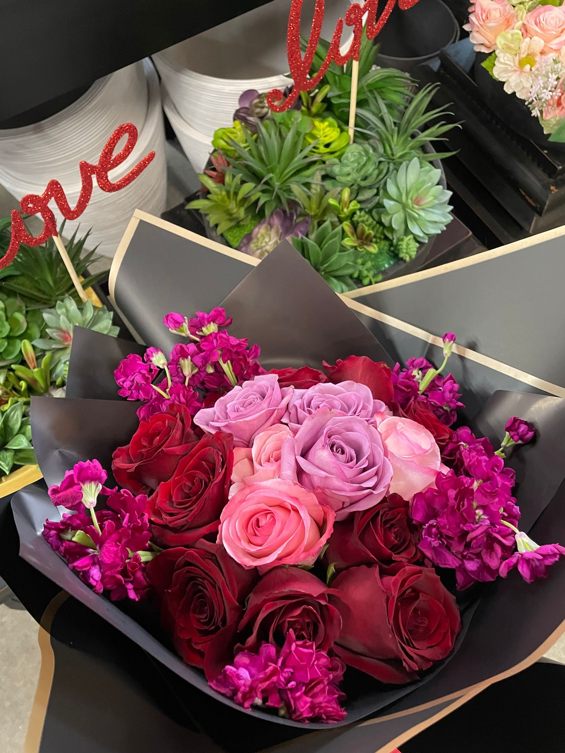 A bouquet of flowers with a love sign in the background