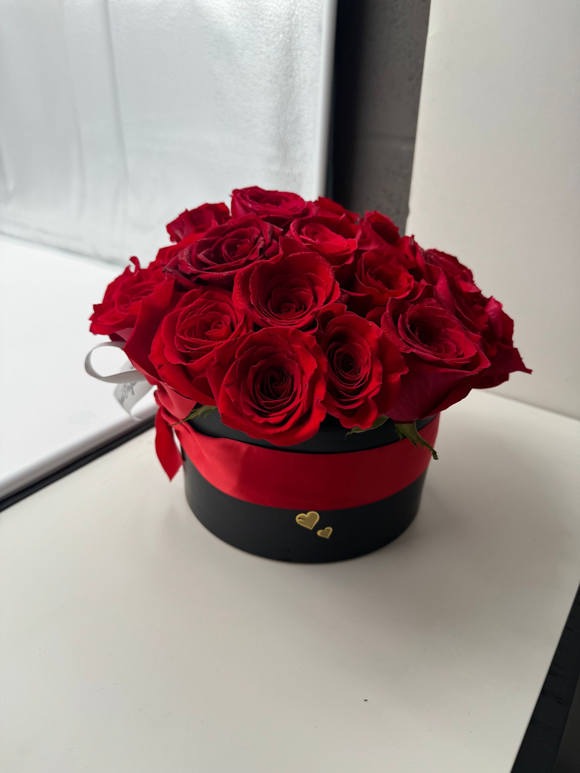 A black box filled with red roses and a red ribbon