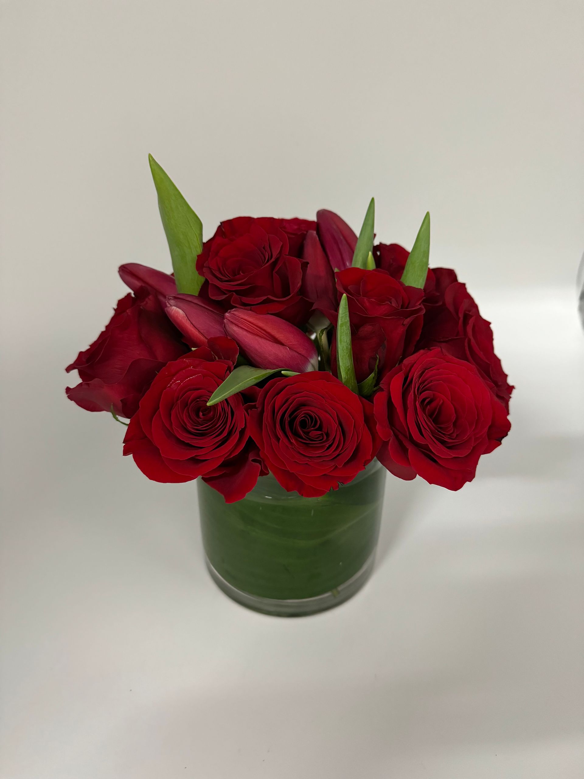 A vase filled with red roses and pink tulips
