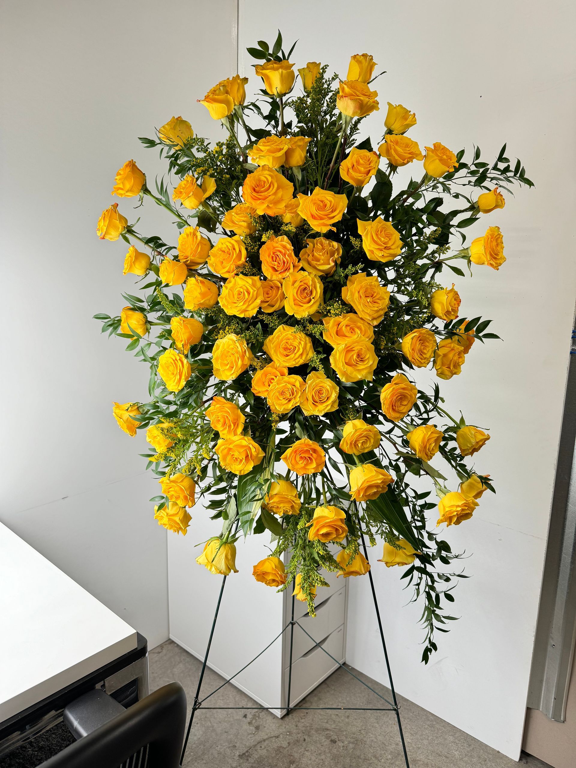 A display of yellow roses on a stand in a room