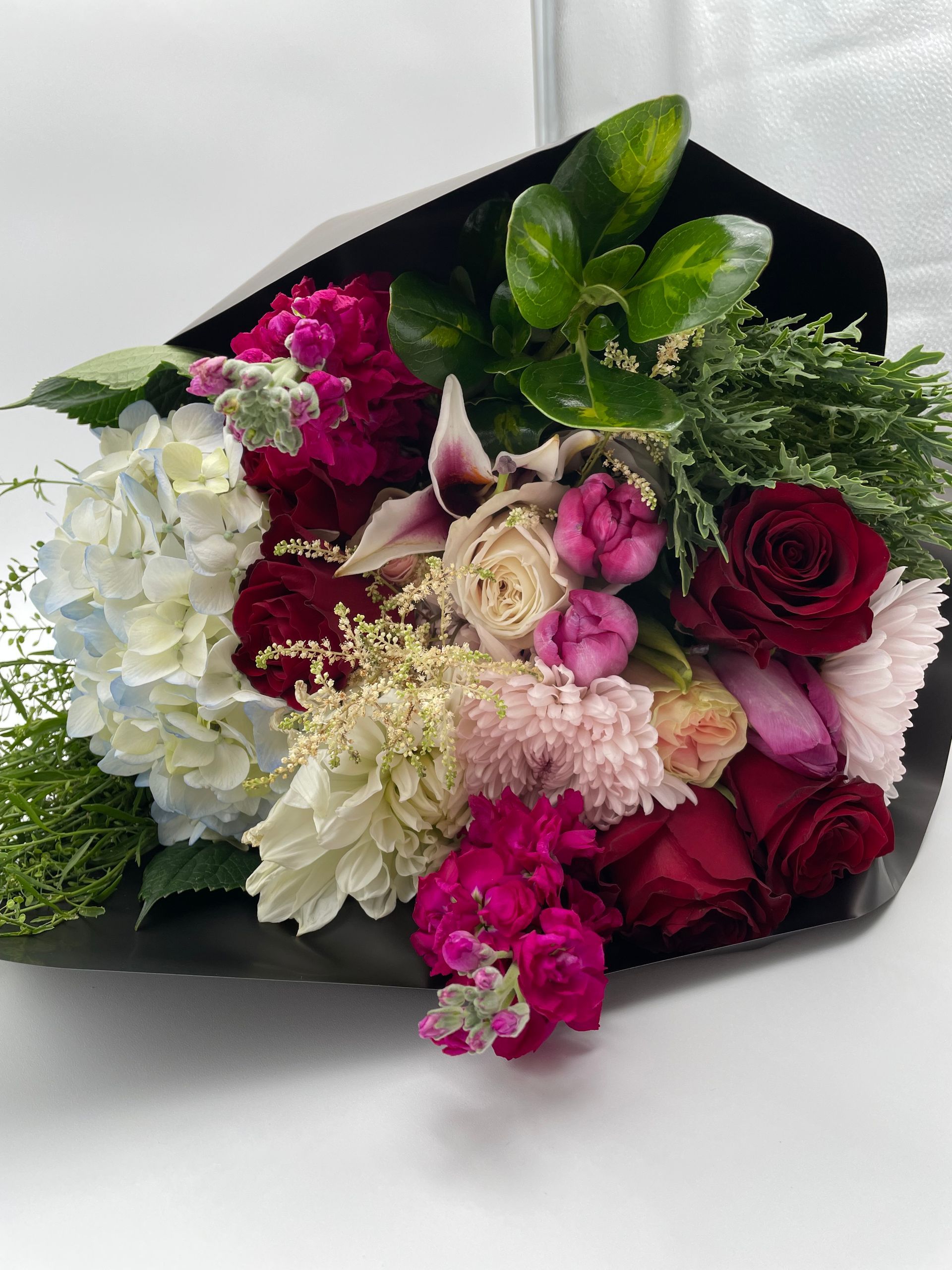 A bouquet of flowers wrapped in black paper on a table.