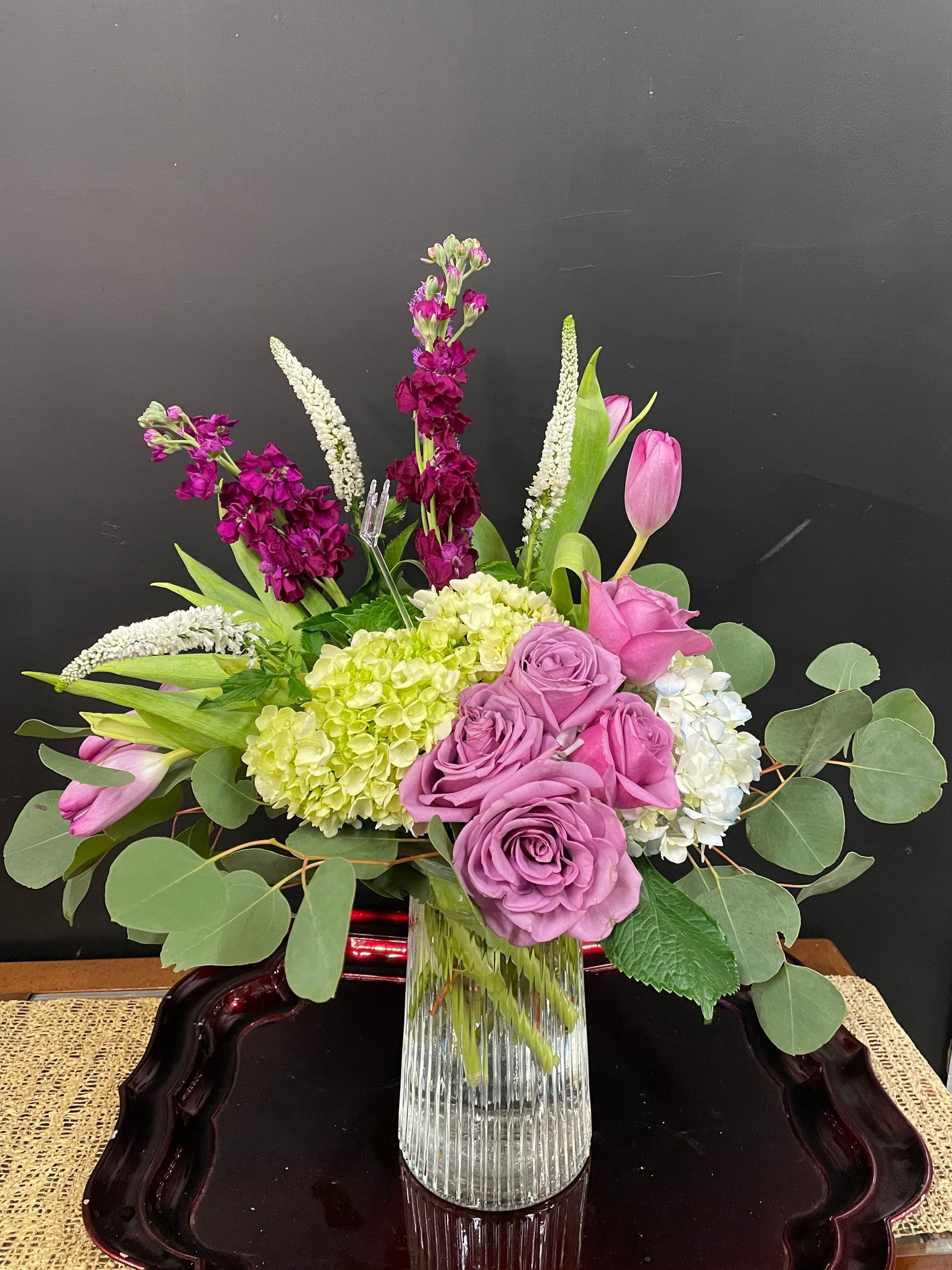 A vase filled with purple and green flowers is sitting on a table.