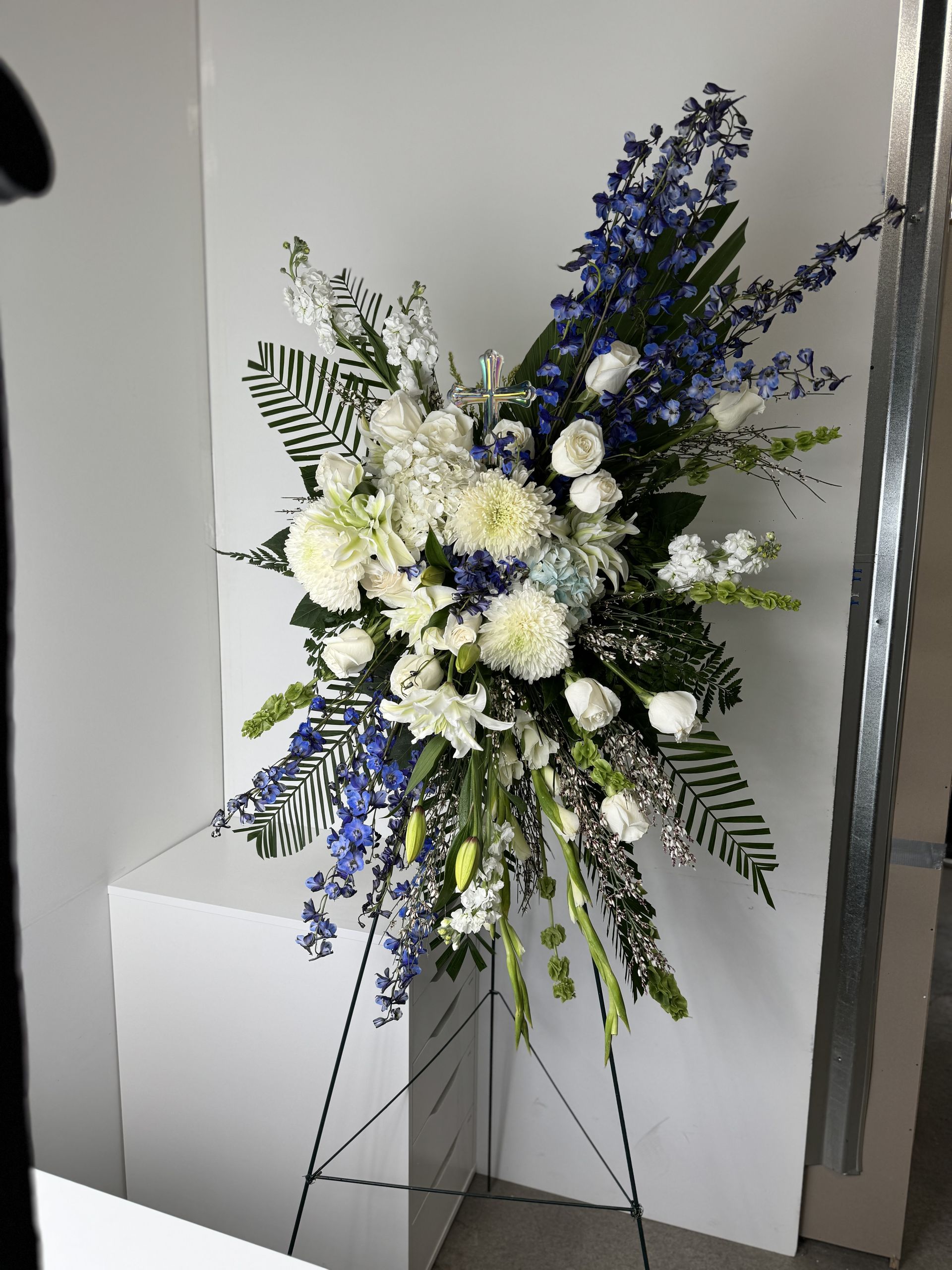A display of blue and white flowers on a stand in a room.