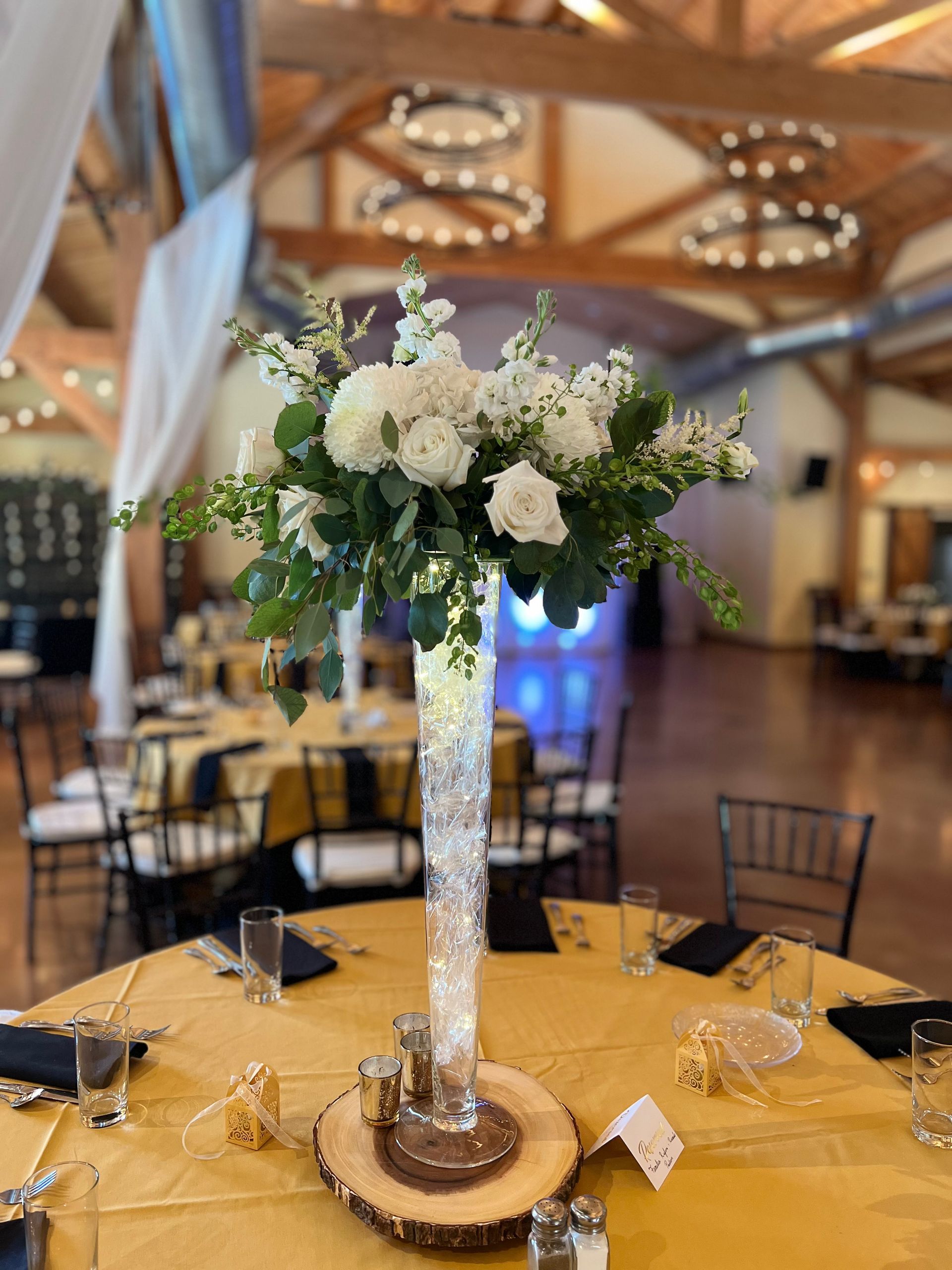 A tall vase filled with white flowers is on a table.