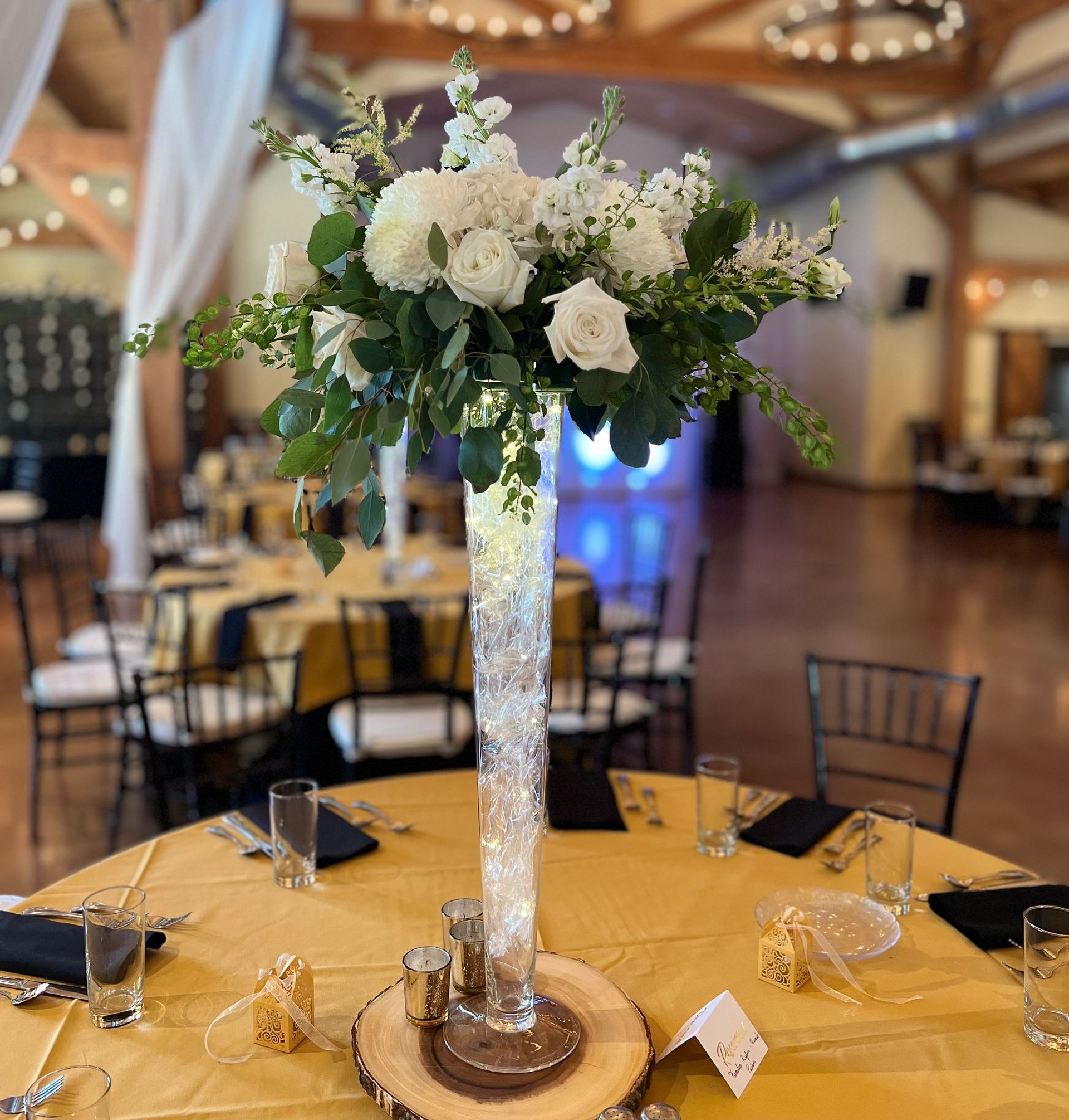 A tall vase filled with white flowers is on a table.