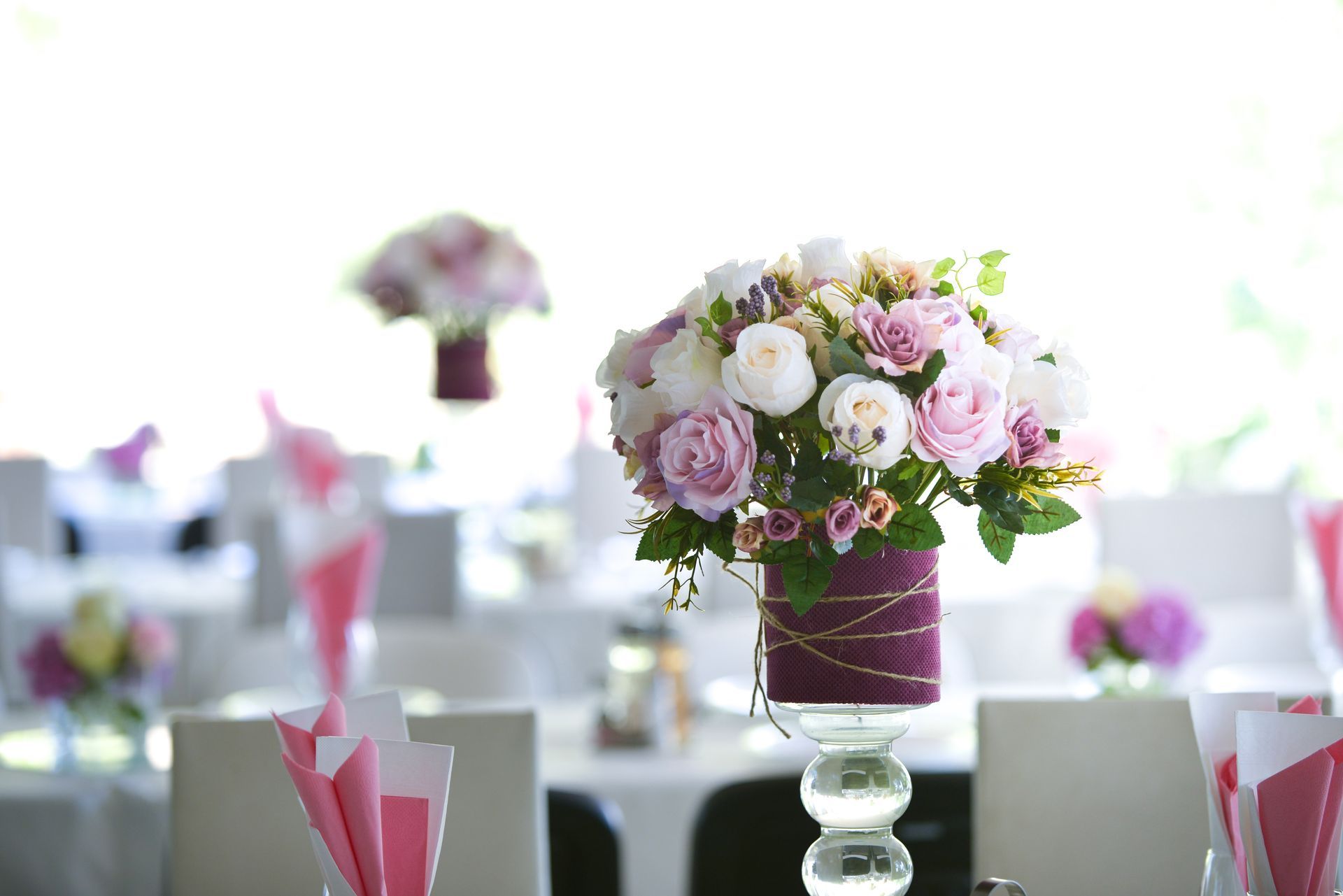 A display of colorful flowers on a stand in front of a white wall.