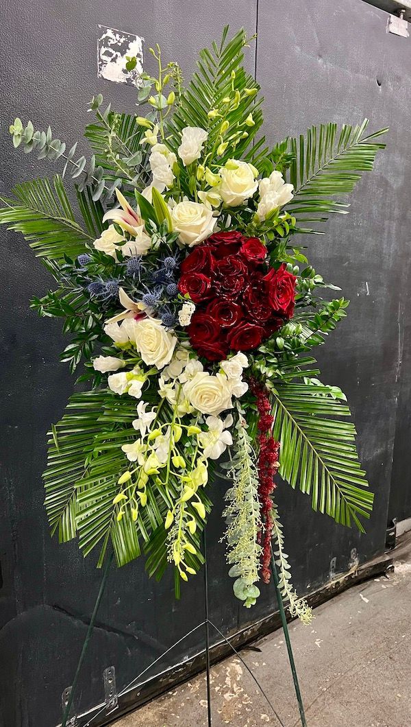 A display of flowers on a stand in front of a black wall.