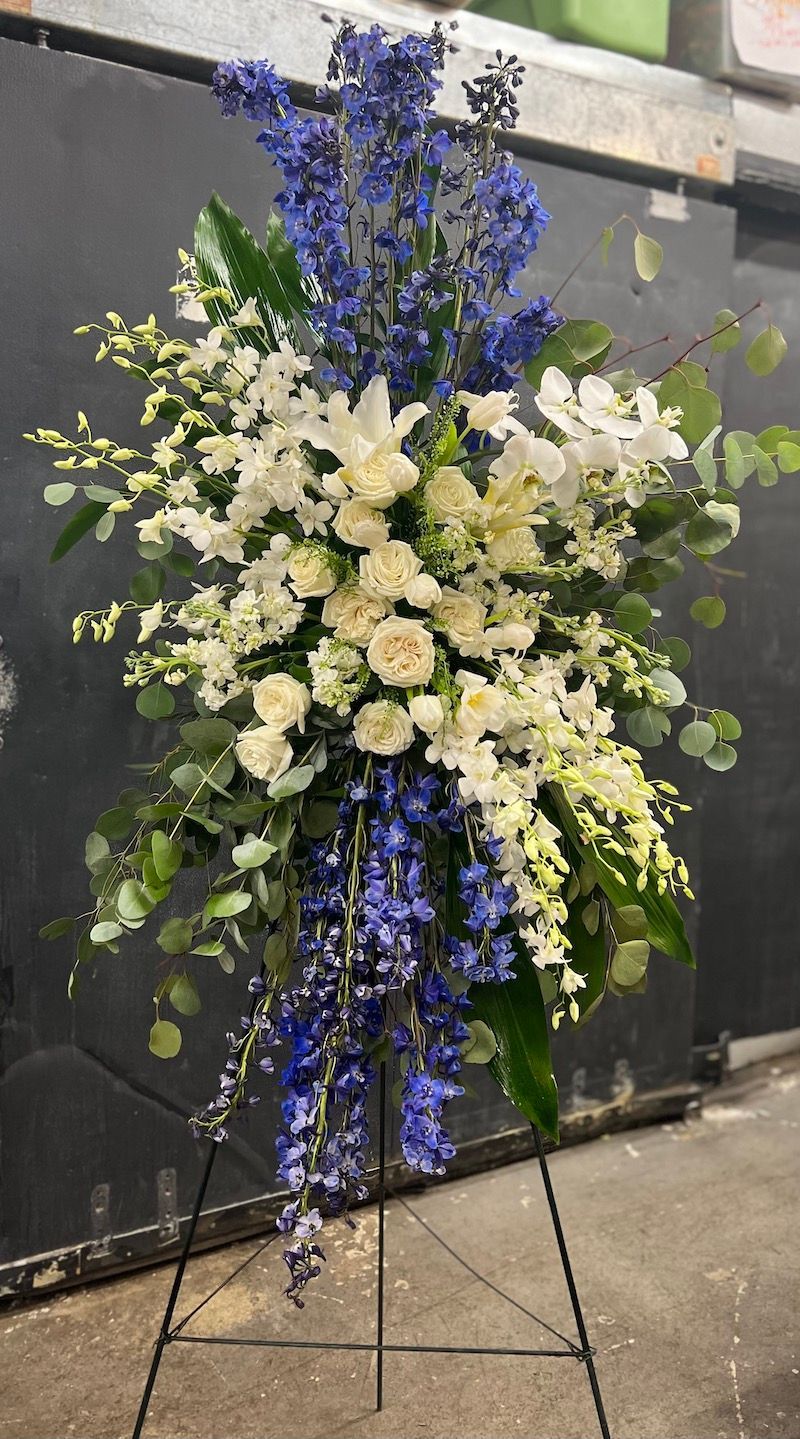 A display of white and blue flowers on a stand.