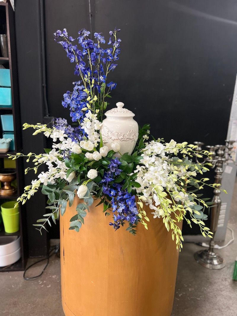A wooden urn filled with blue and white flowers.