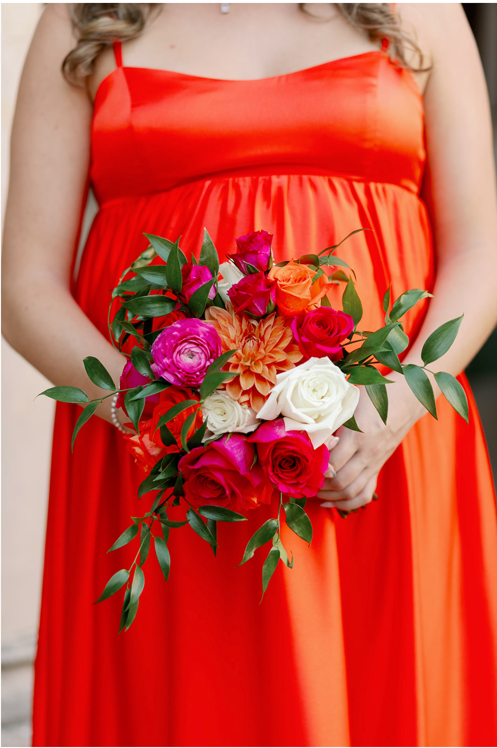 A woman in a red dress is holding a bouquet of flowers.