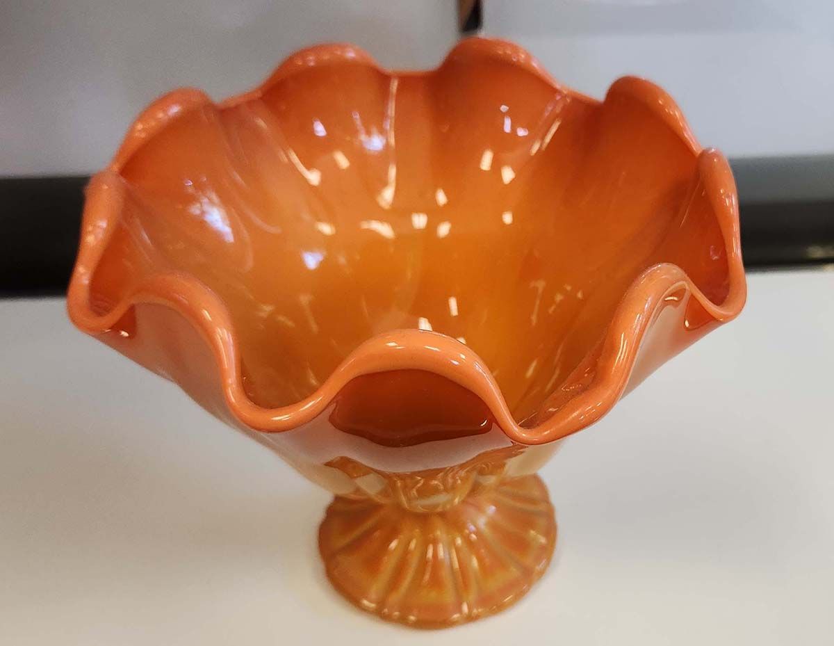 An orange bowl with a ruffled rim sits on a table