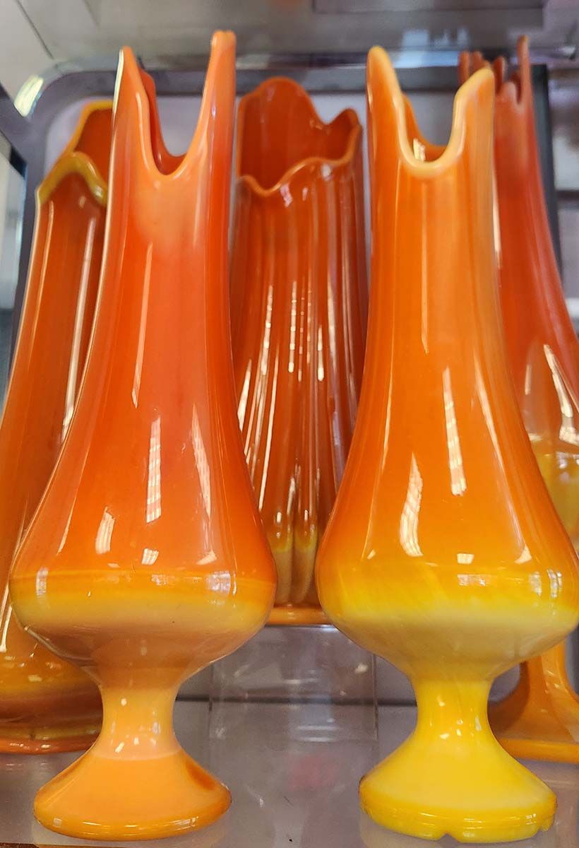 A row of orange and yellow vases on a shelf
