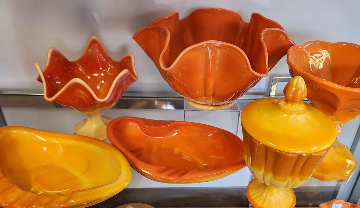 A bunch of orange bowls are sitting on a shelf