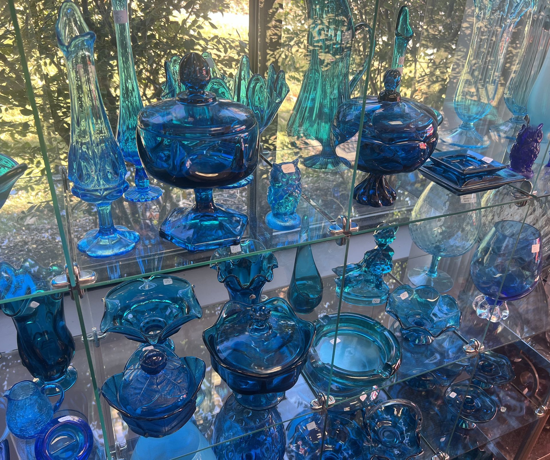 A display case filled with lots of blue glass items