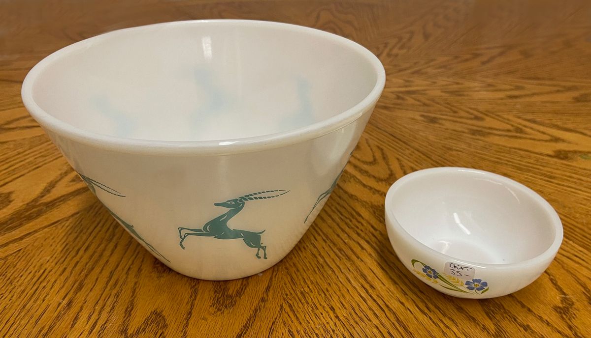 A white bowl with a deer on it sits next to a smaller bowl