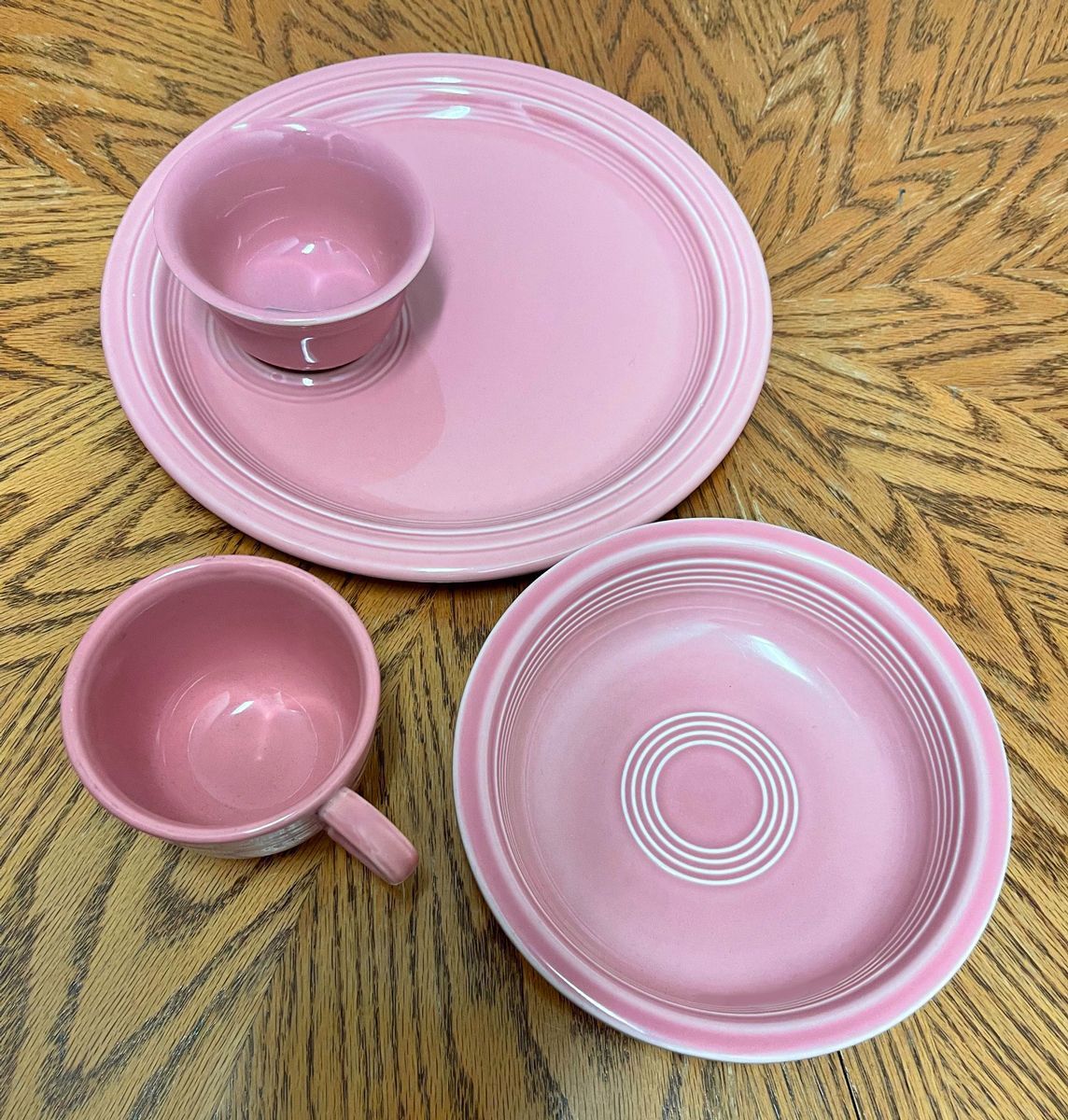 A set of pink plates and cups on a wooden table