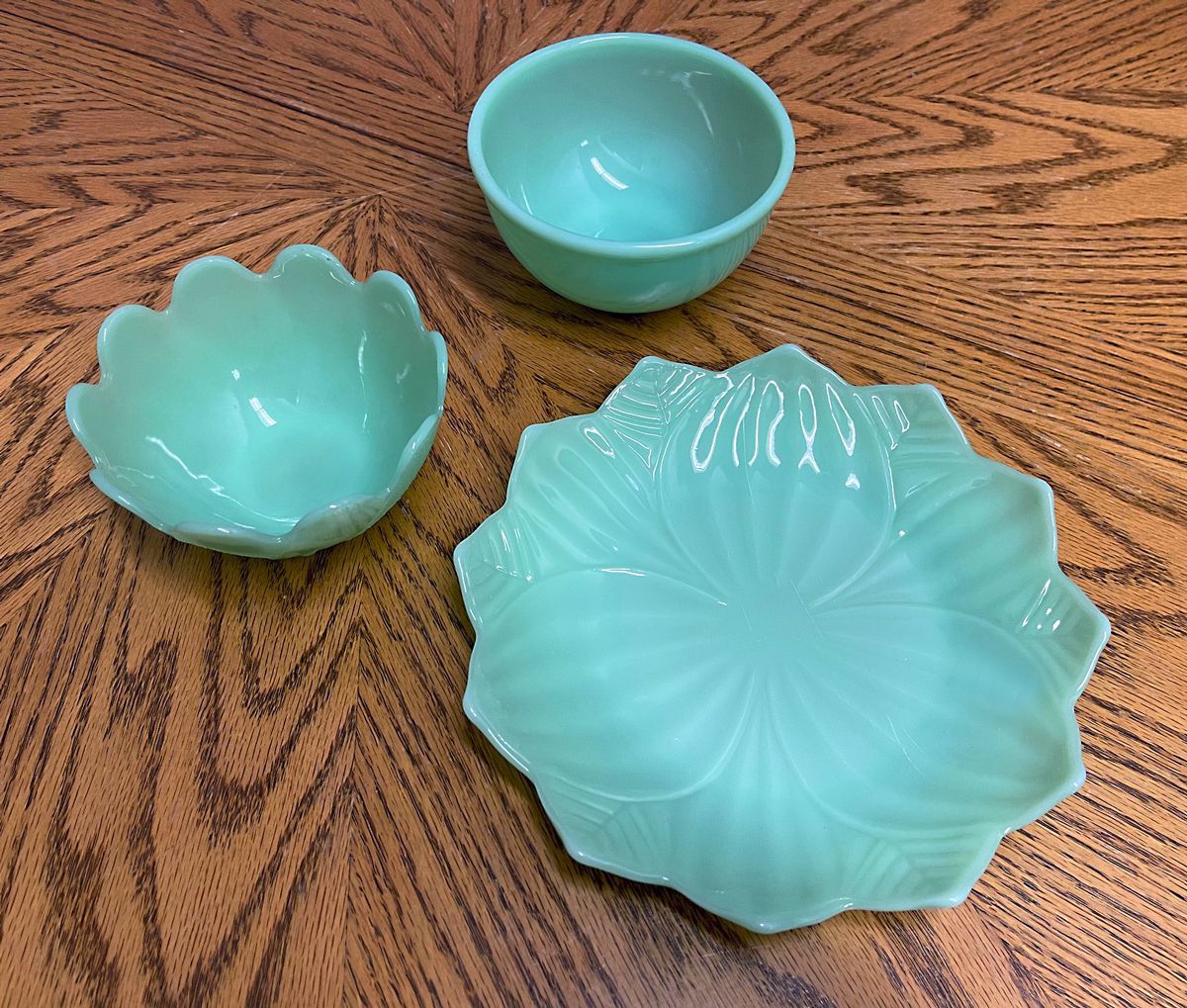 Three green bowls and a plate on a wooden table