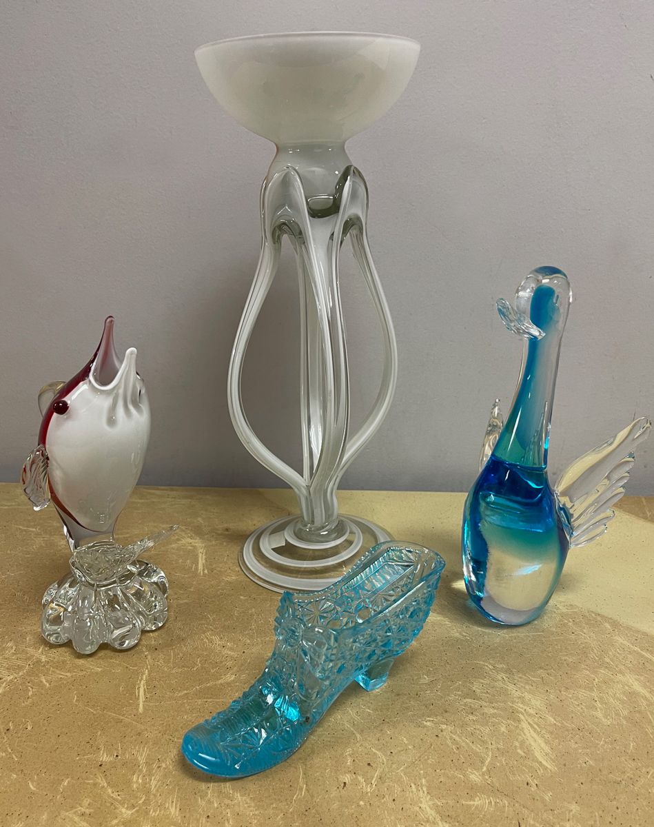 Three glass figurines are on a table including a fish a shoe and a bird
