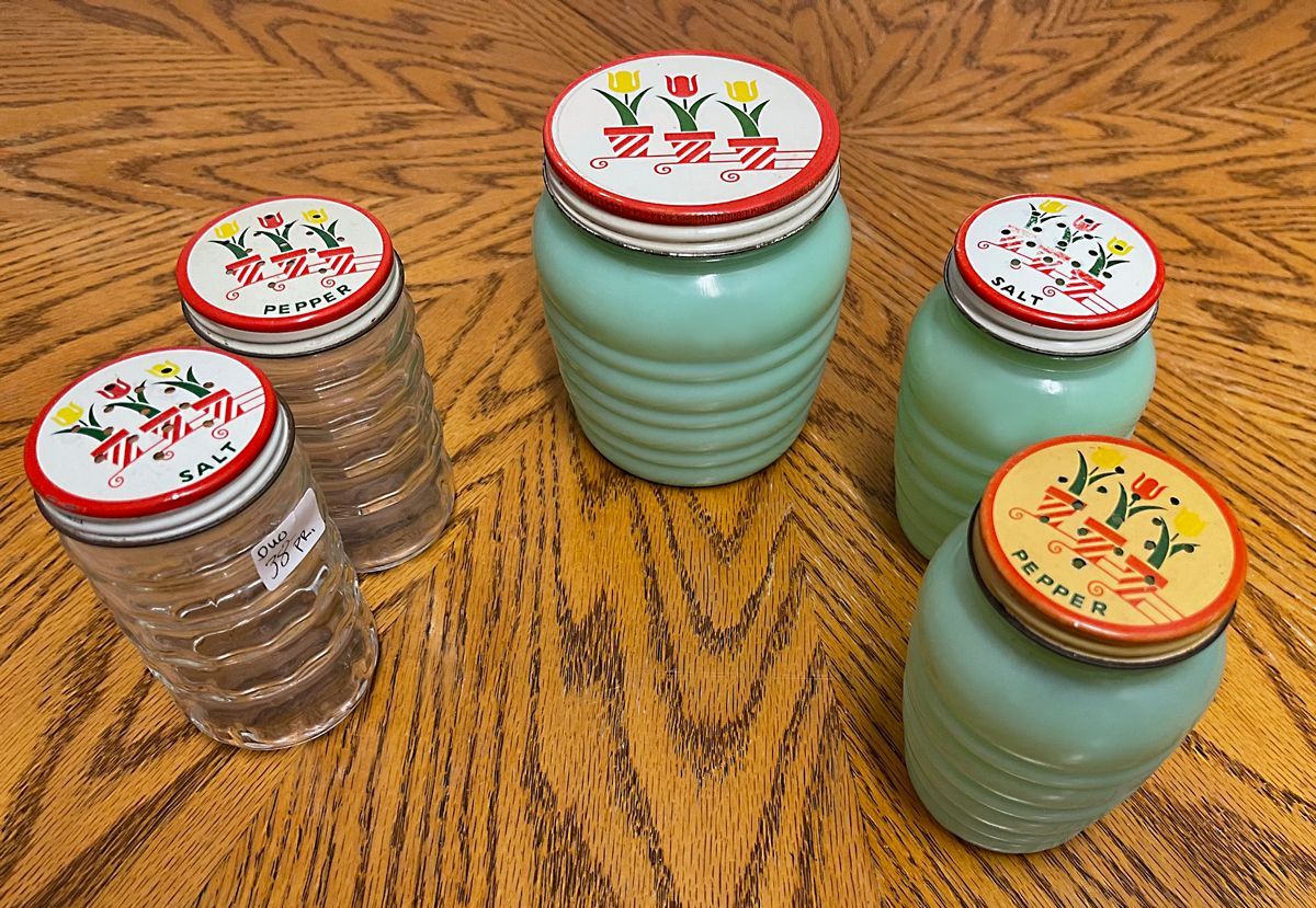 Several jars on a wooden table one of which has a floral design on the lid