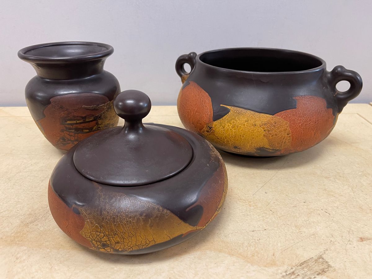 Three clay pots are sitting on a wooden table