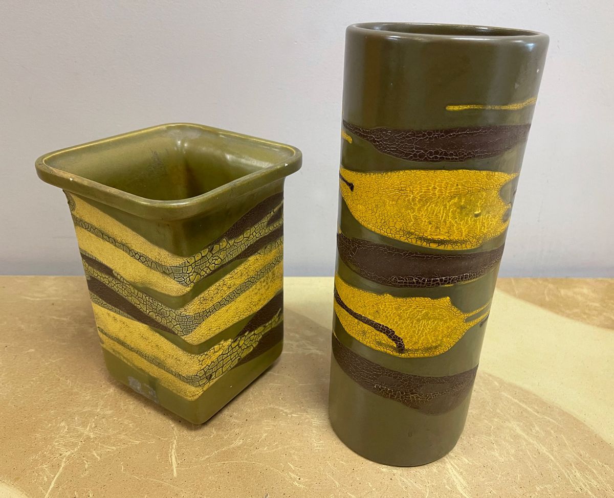 Two green and yellow vases are sitting on a table