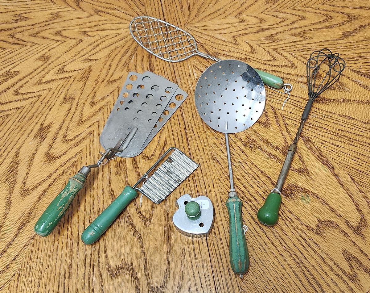 A set of kitchen utensils with green handles on a wooden table