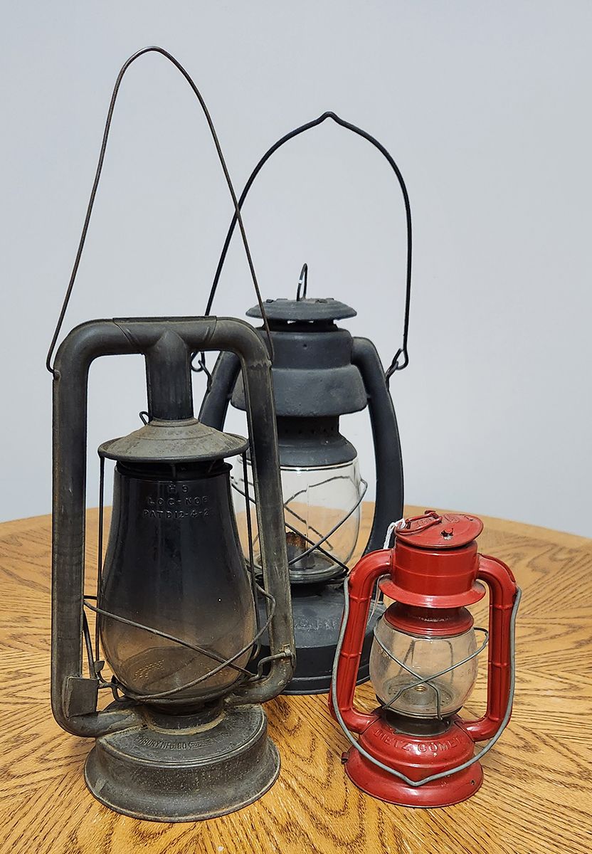 Three old lanterns are sitting on a wooden table