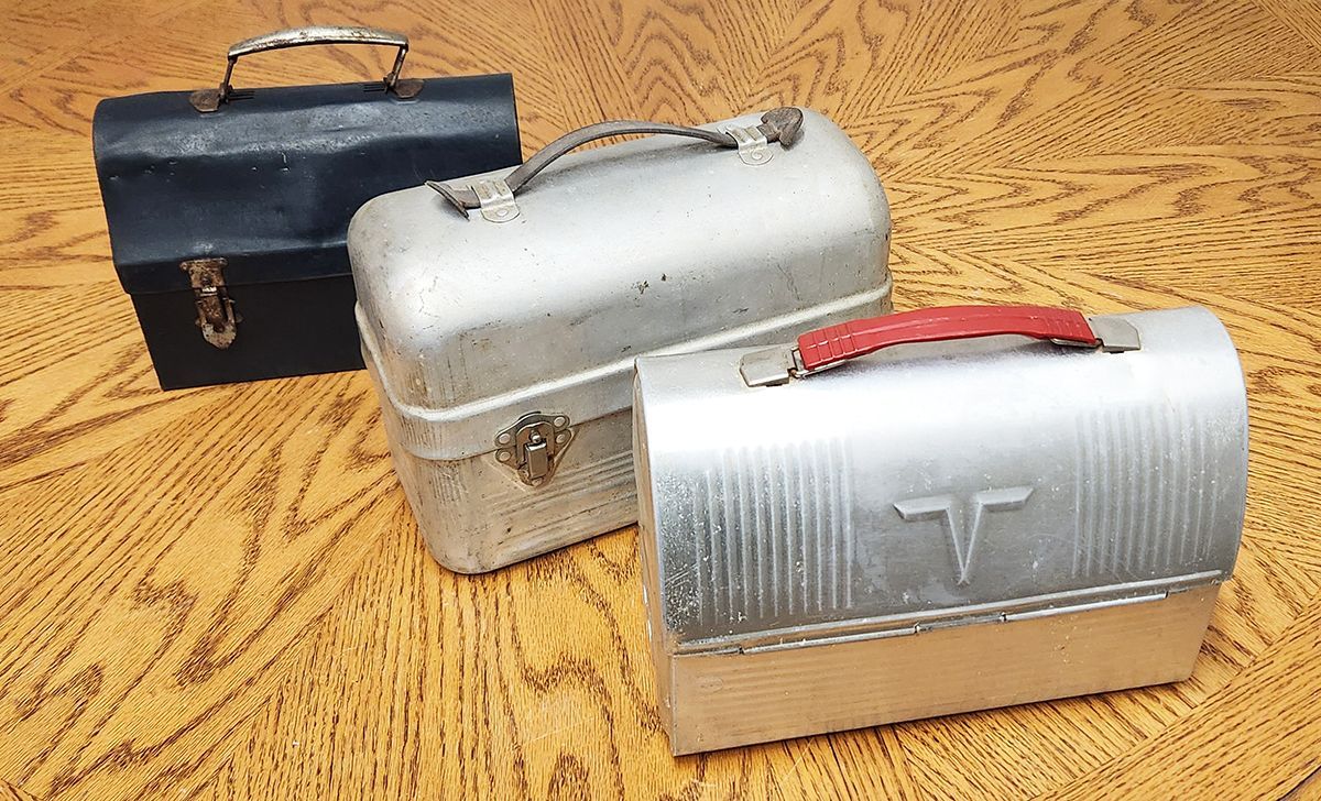 Three metal lunch boxes are sitting on a table