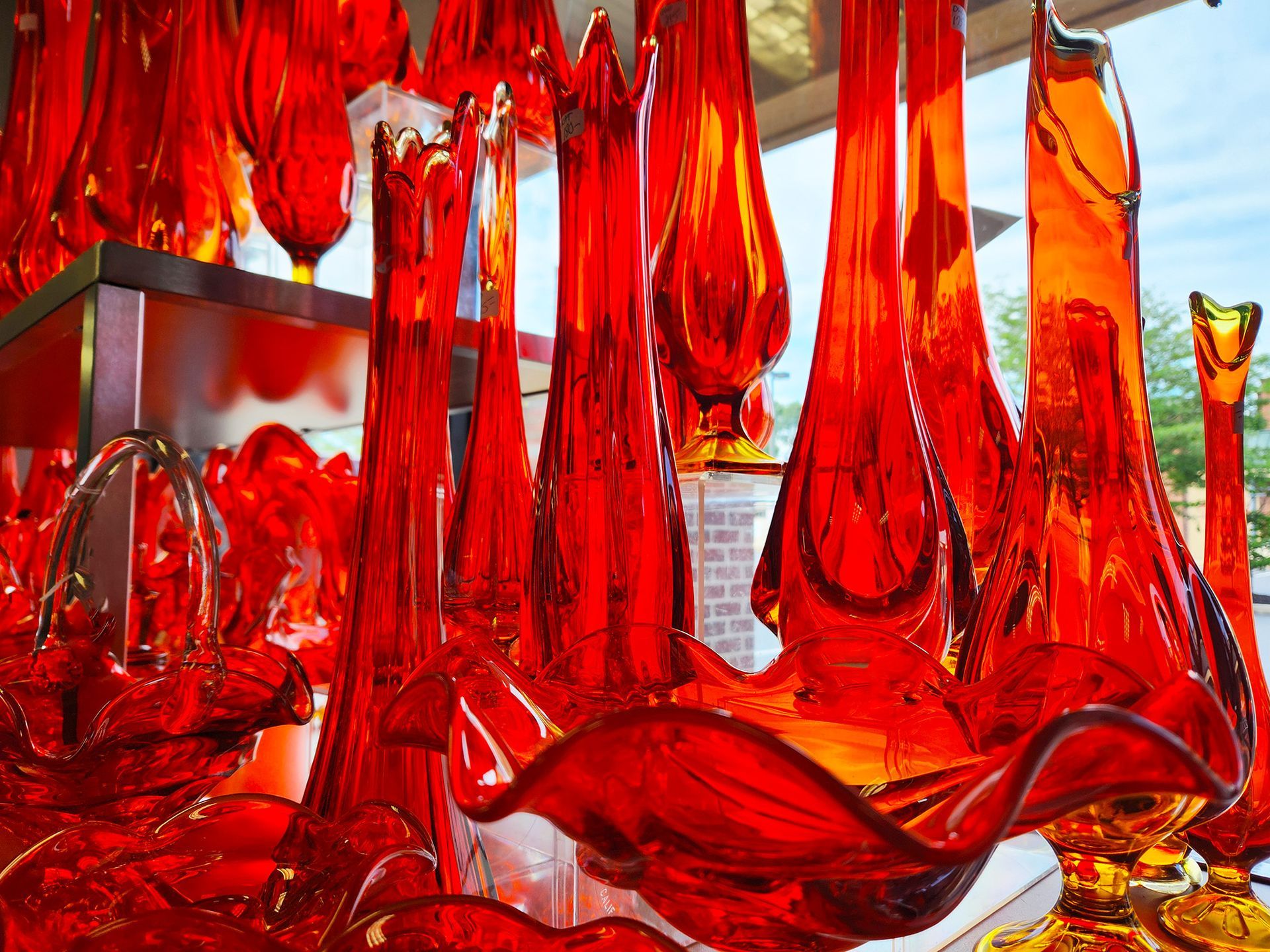 A bunch of red glass vases are displayed in a window