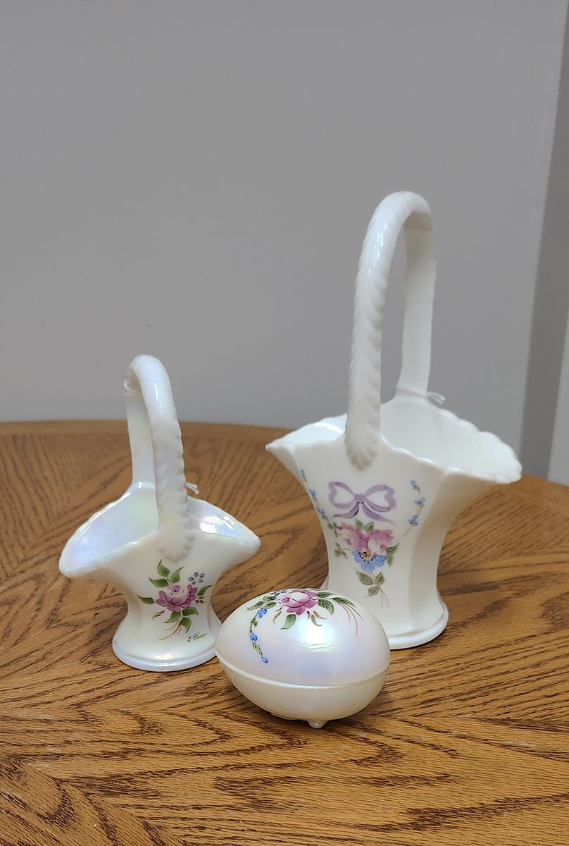 Three white ceramic baskets with flowers on them are on a wooden table