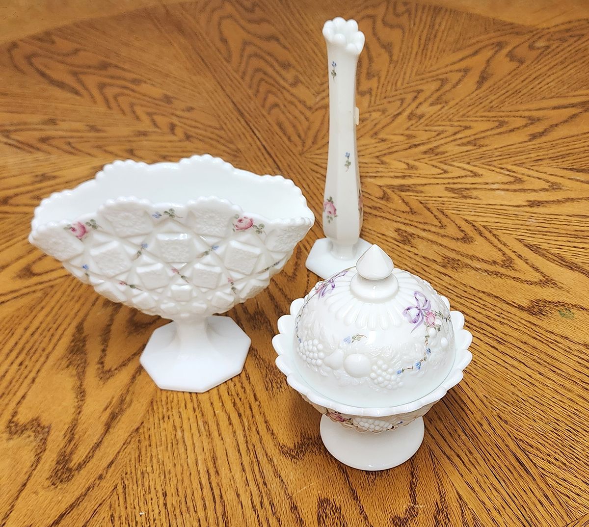 Two white vases with flowers on them are on a wooden table