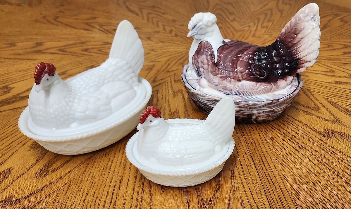 Three white chickens are sitting on a wooden table