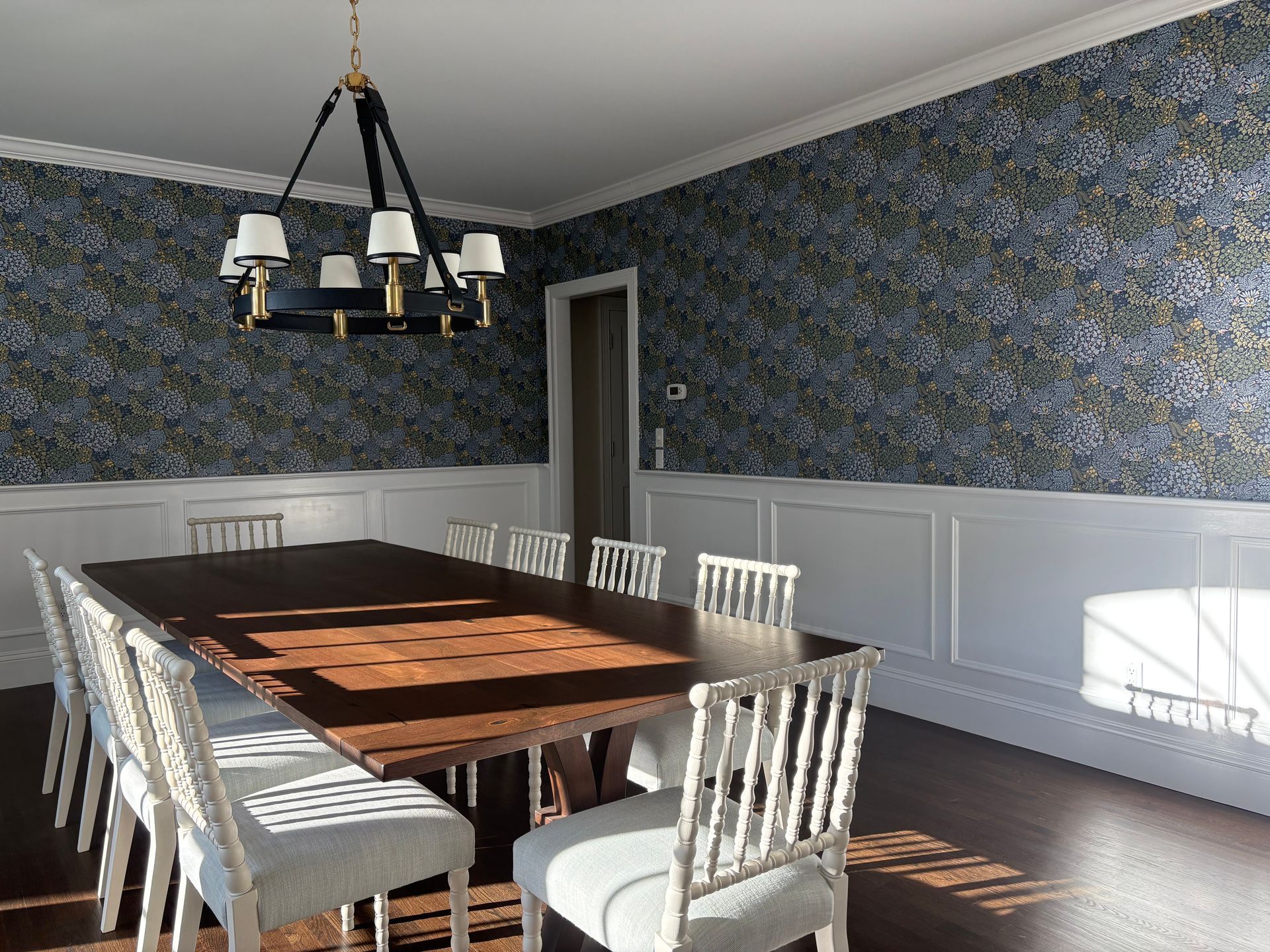 Dining room with blue-green wallpaper and white wainscoting.