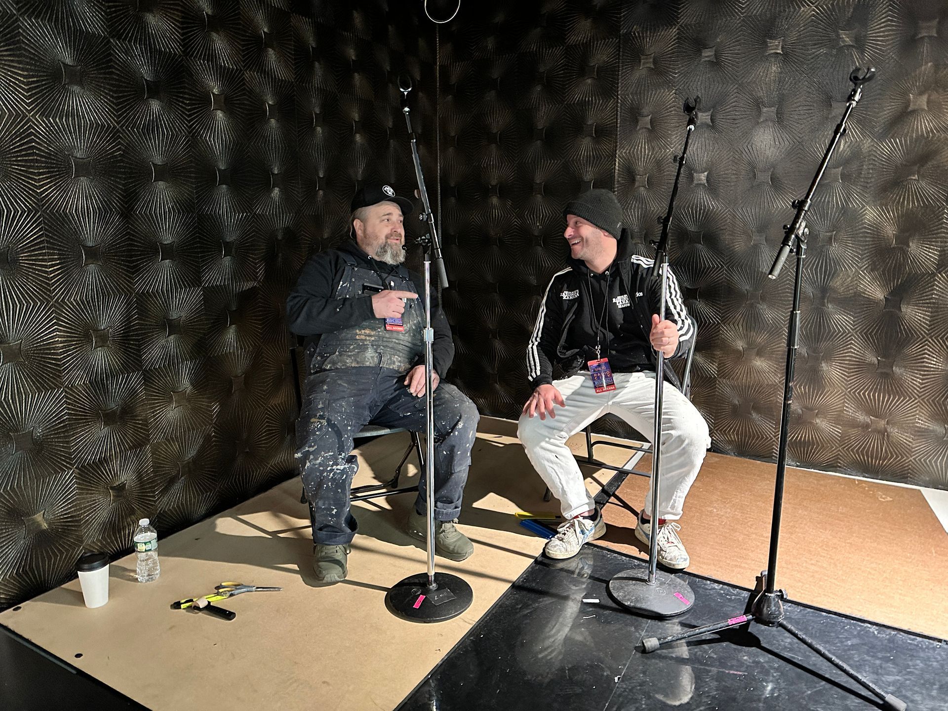 Interview setup: dark textured mural behind seated podcast guests.