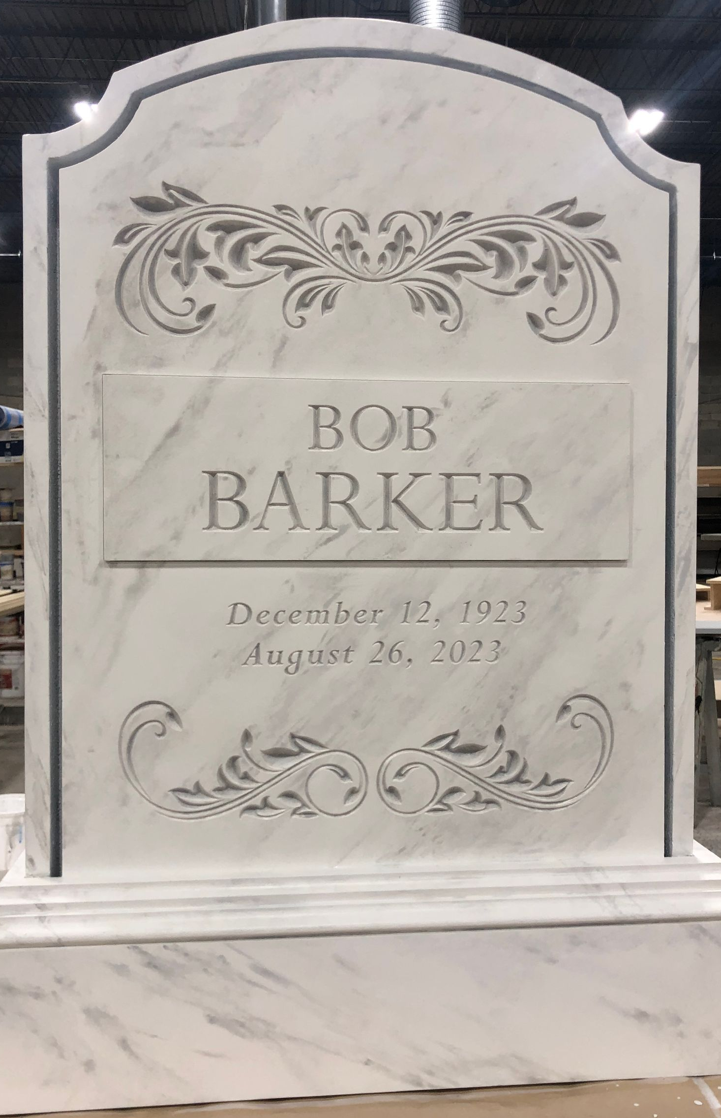 Marble gravestone for Bob Barker with floral carvings and dates.