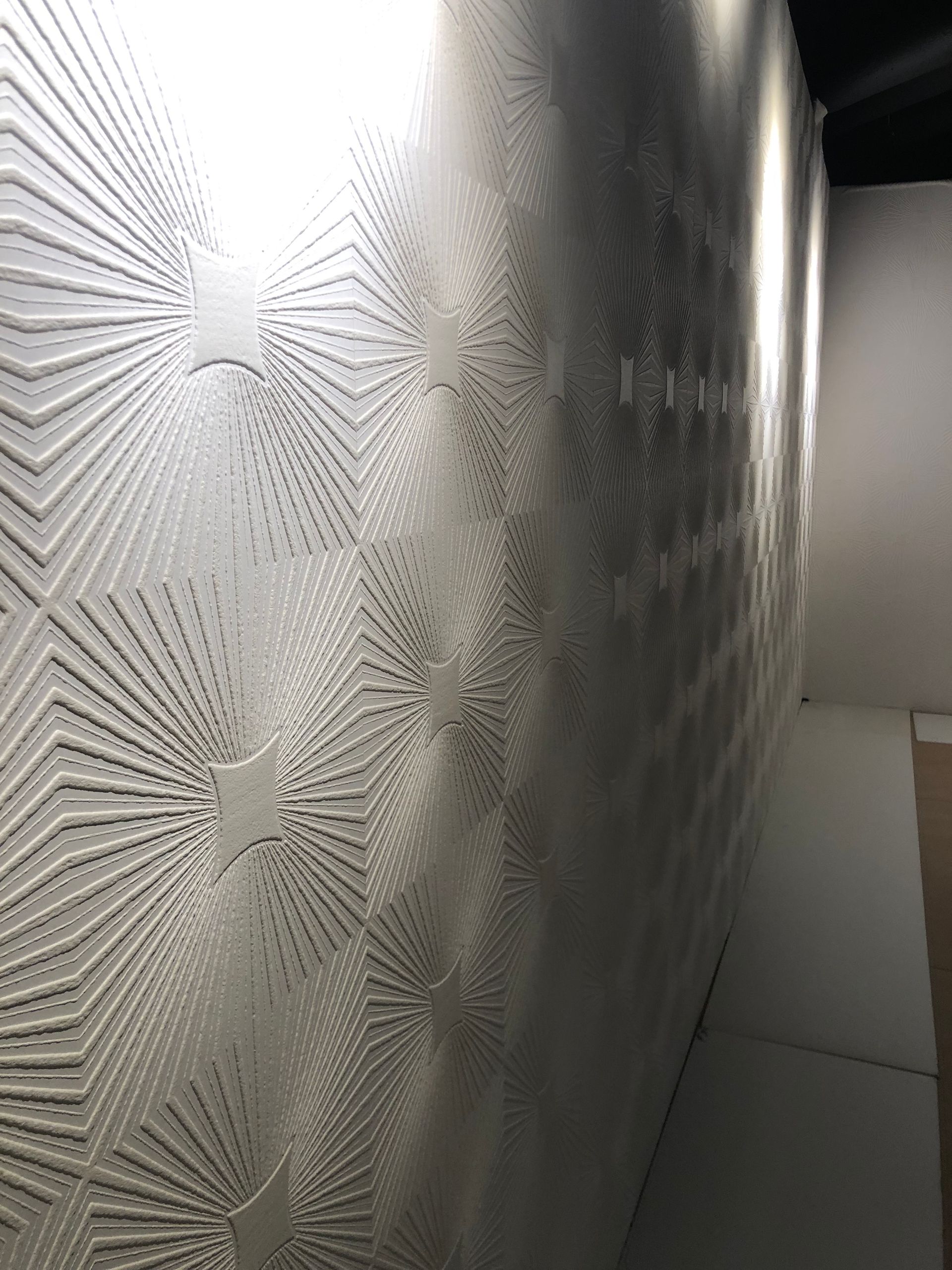 Geometric mural with starburst texture and light tile flooring.