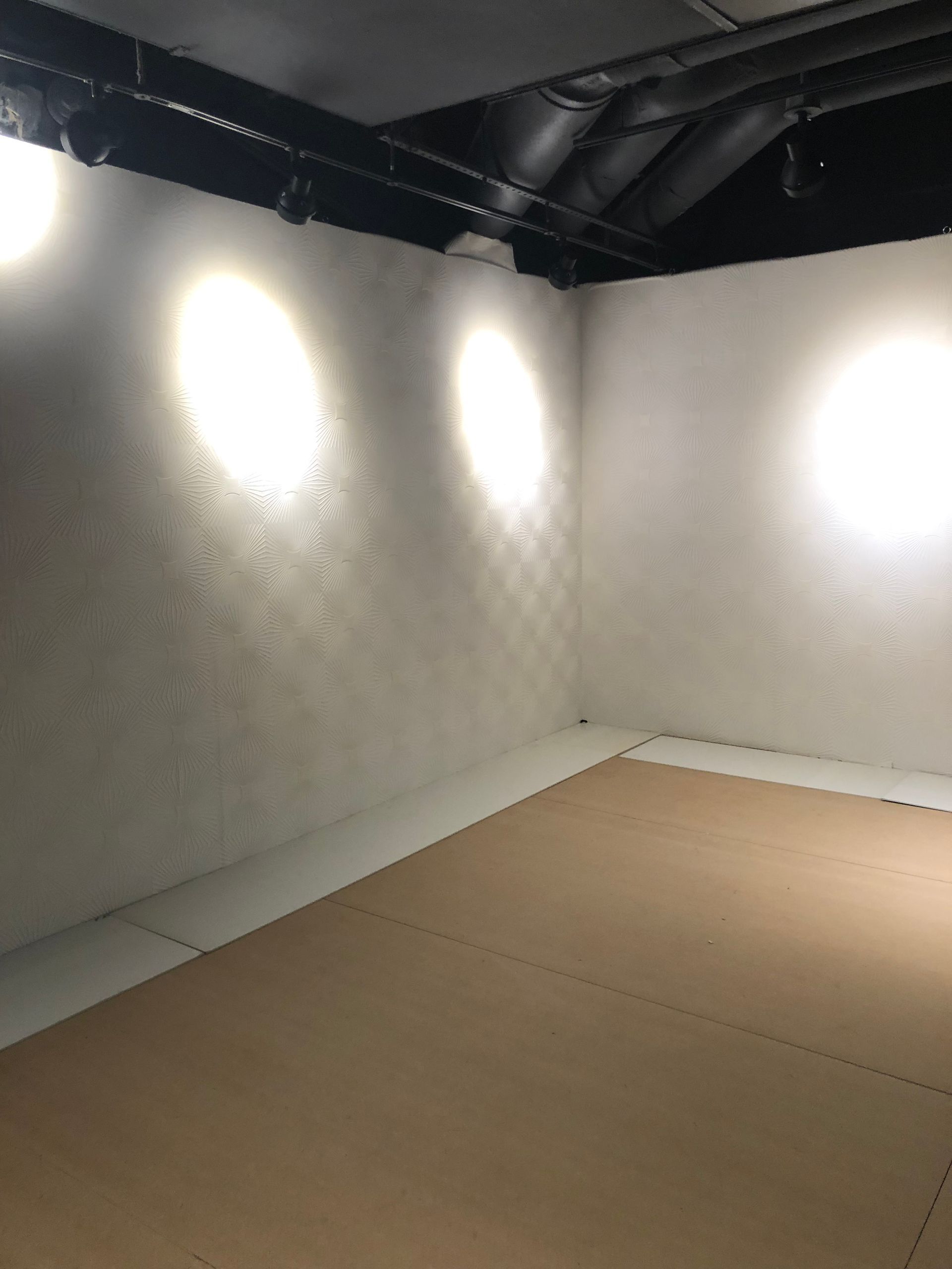 White textured mural with geometric pattern and spotlight-lit floor.