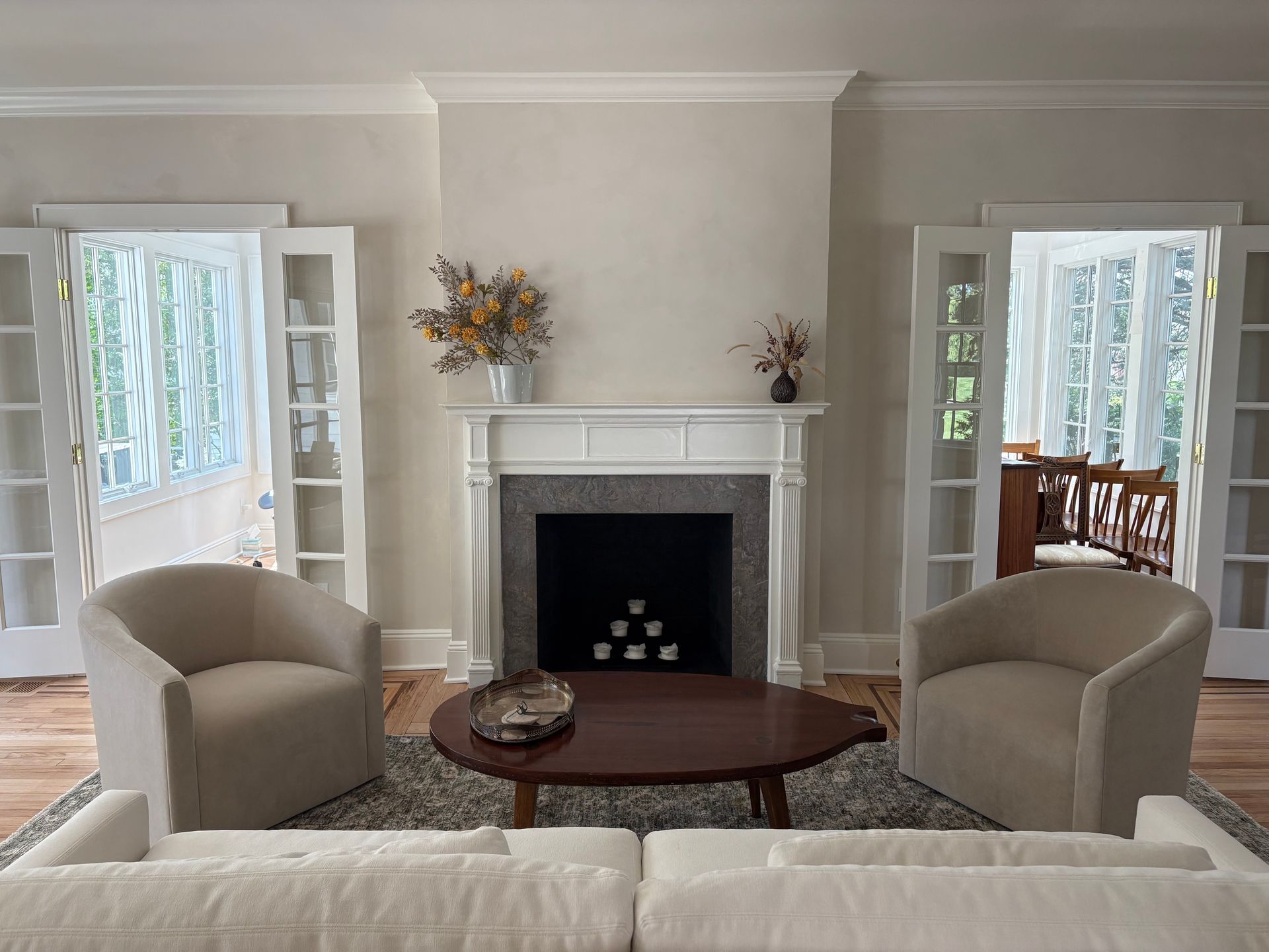 Living room and white fireplace, armchairs, and French doors.