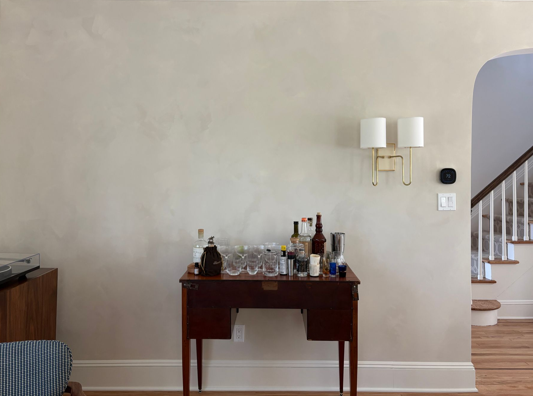 Home bar setup with bottles, glasses, and brass light fixture.