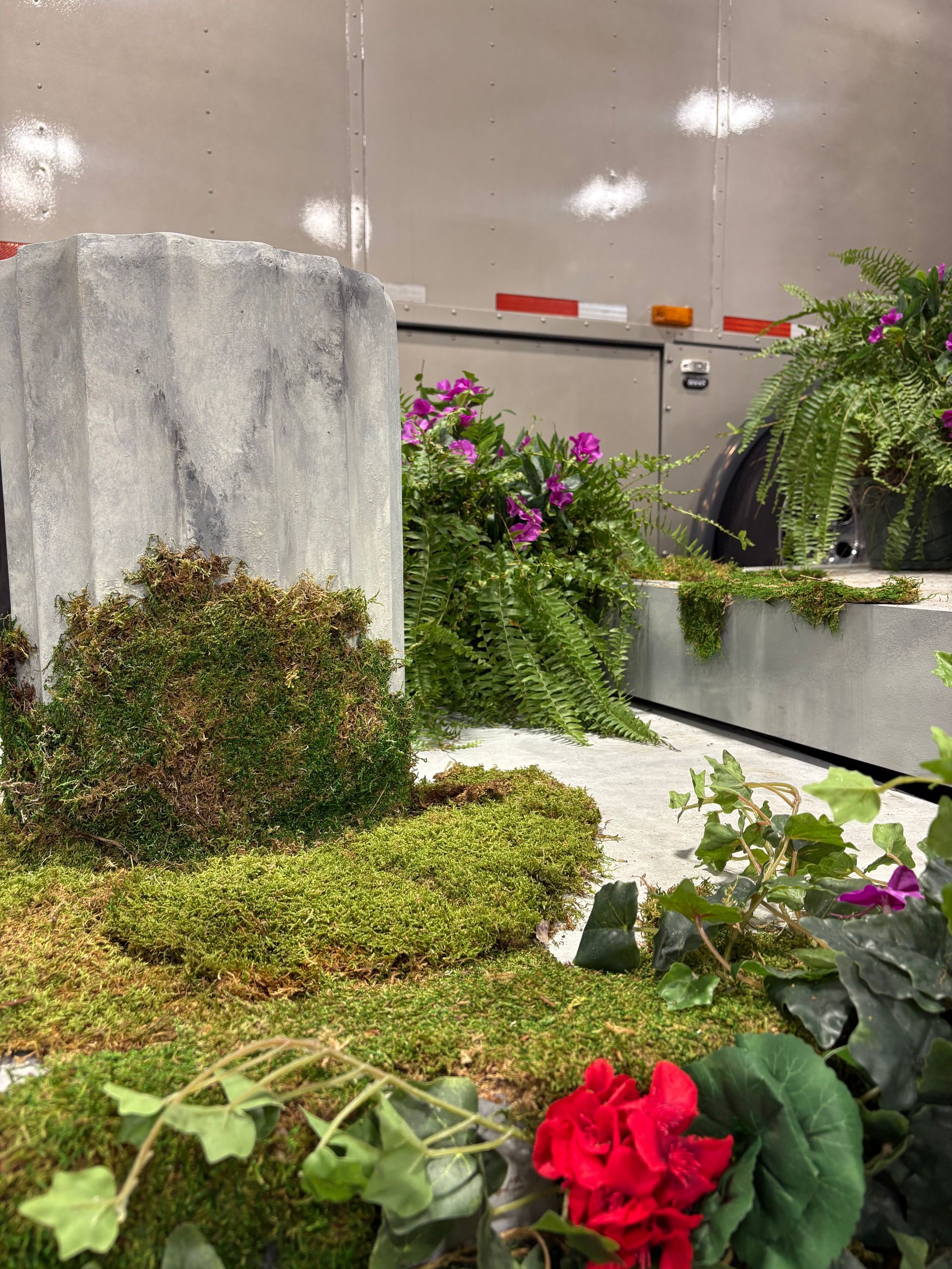Faux garden with mossy base and vibrant artificial flowers.