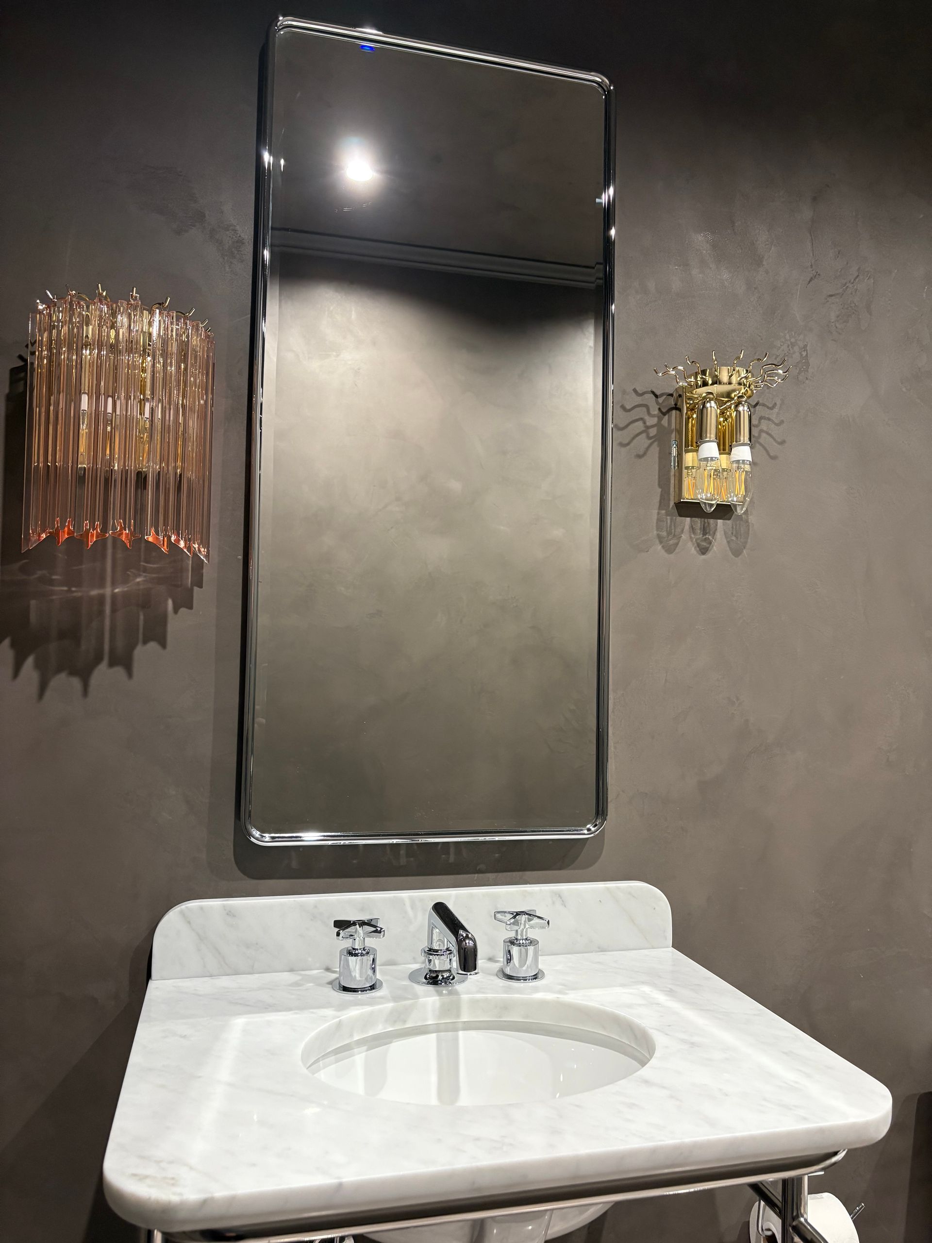 Bathroom with marble vanity, mirror, and dual light fixtures.
